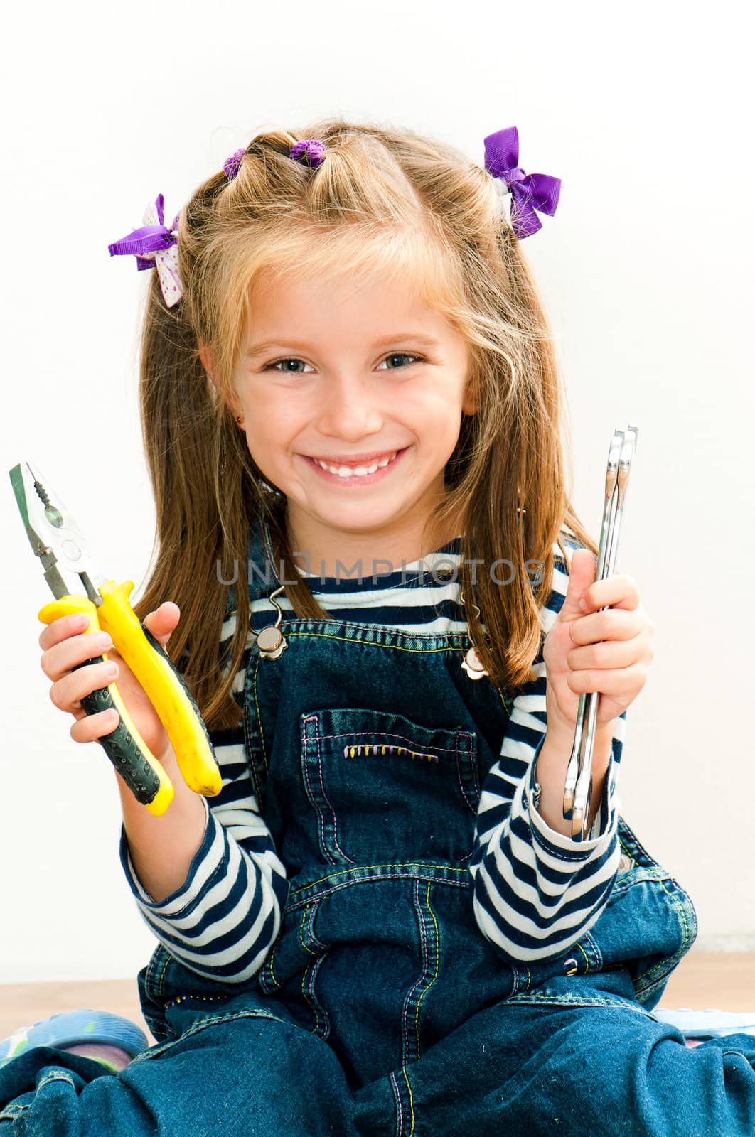 little smiling girl with old pliers and wrench
