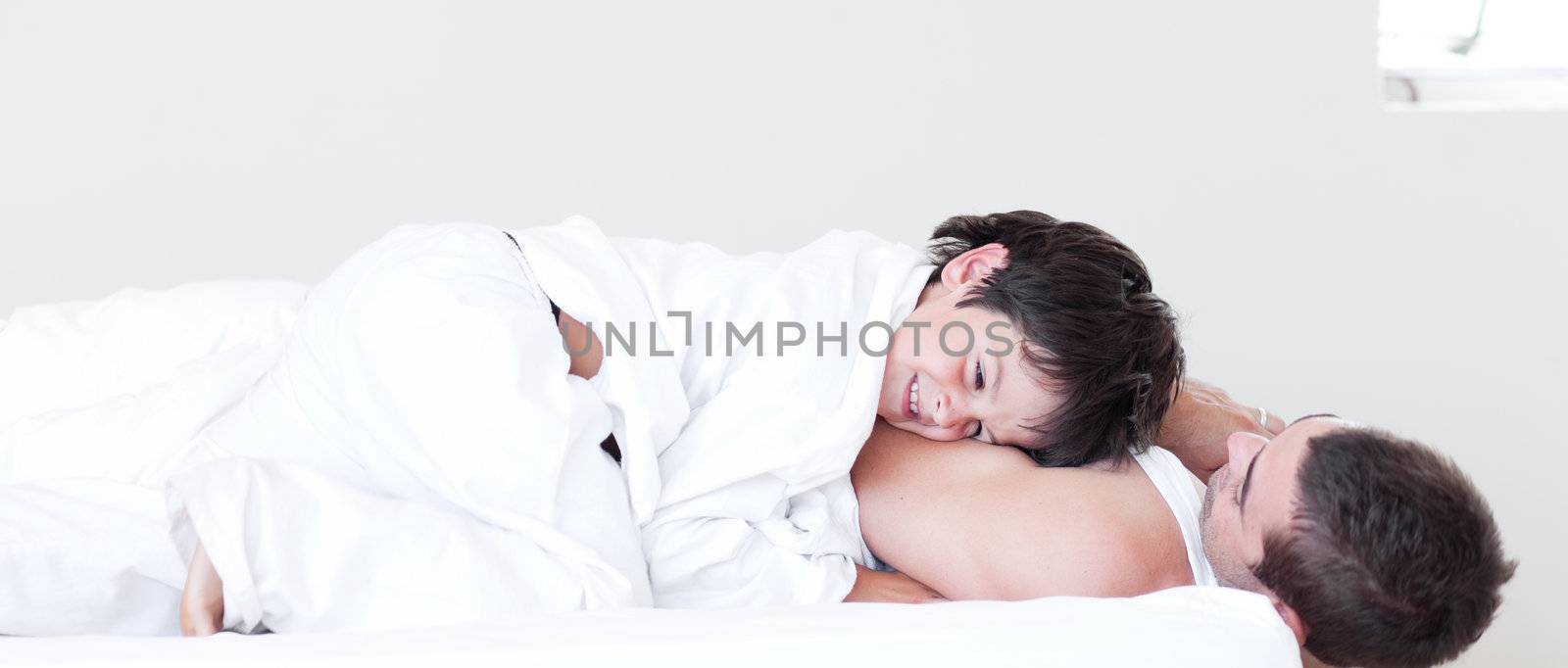 Handsome father and his son looking at the camera on the bed at home