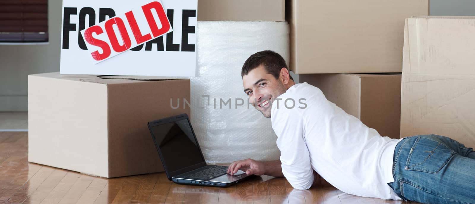 Young man lying on the floor using a laptop by Wavebreakmedia