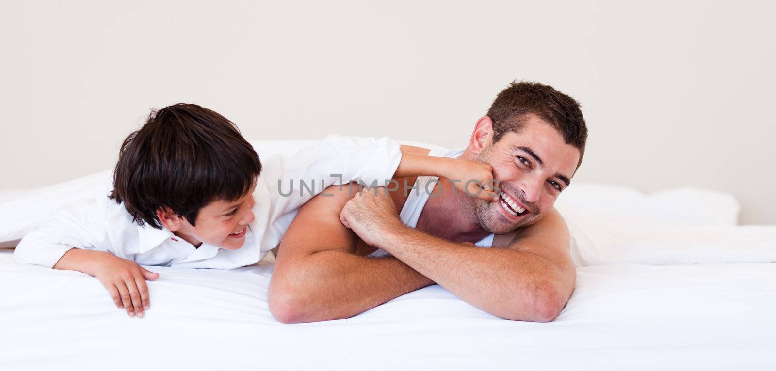 Father and his son having fun on a bed by Wavebreakmedia