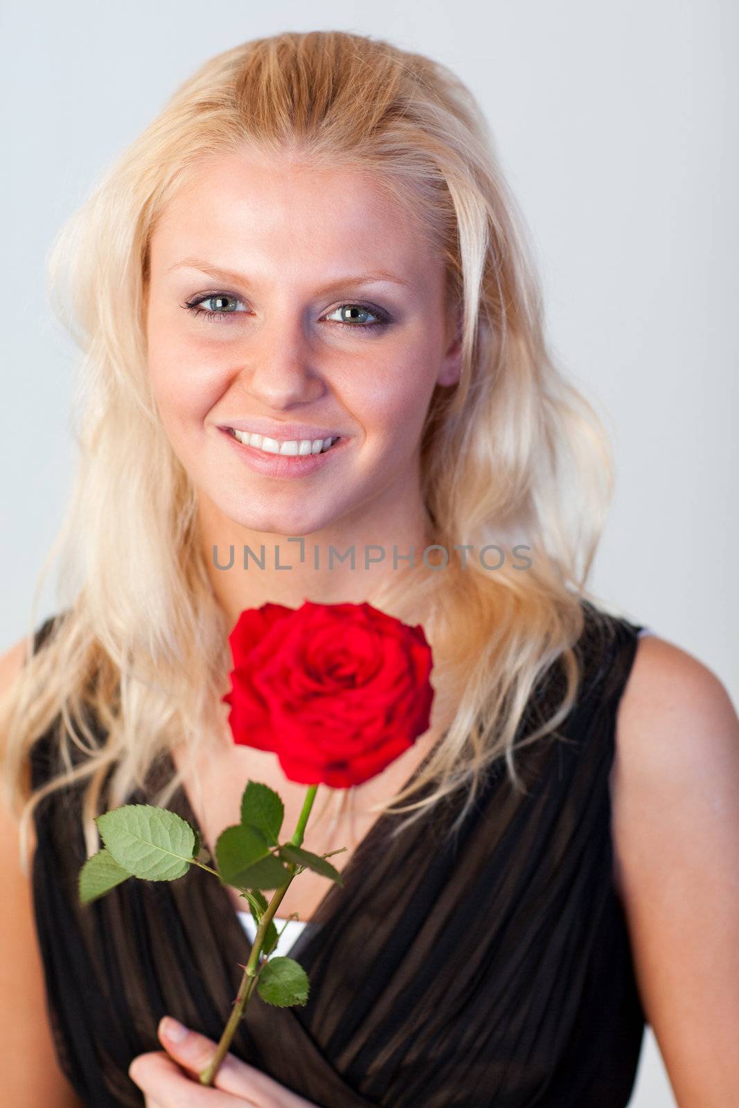 Portrait of an attractive woman with a red rose and smiling at the camera with focus on woman 