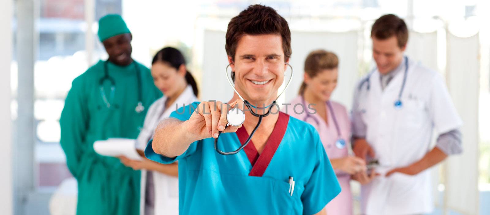 Friendly doctor with his team in the background in hospital