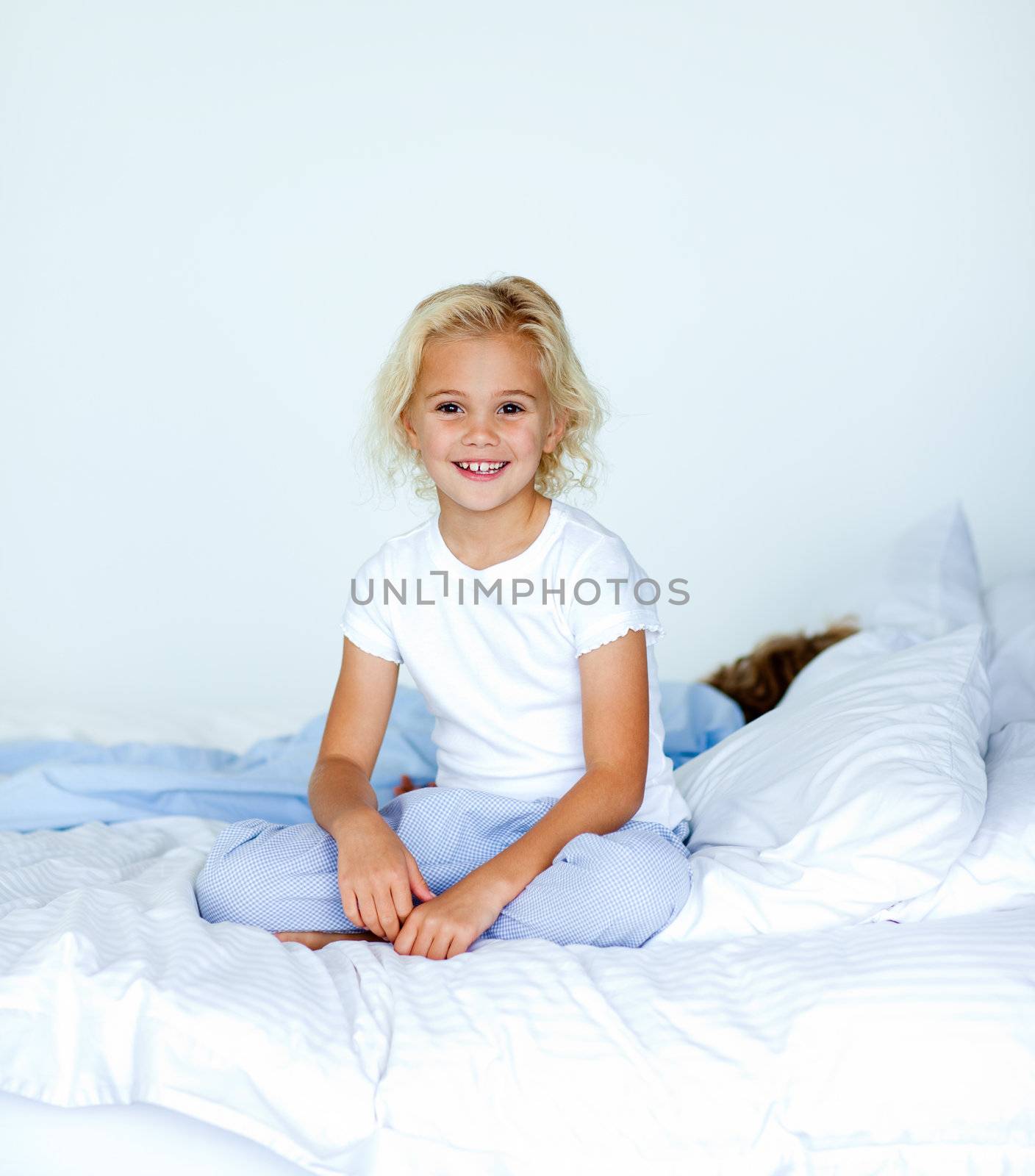 Smiling blonde girl sitting on a bed by Wavebreakmedia
