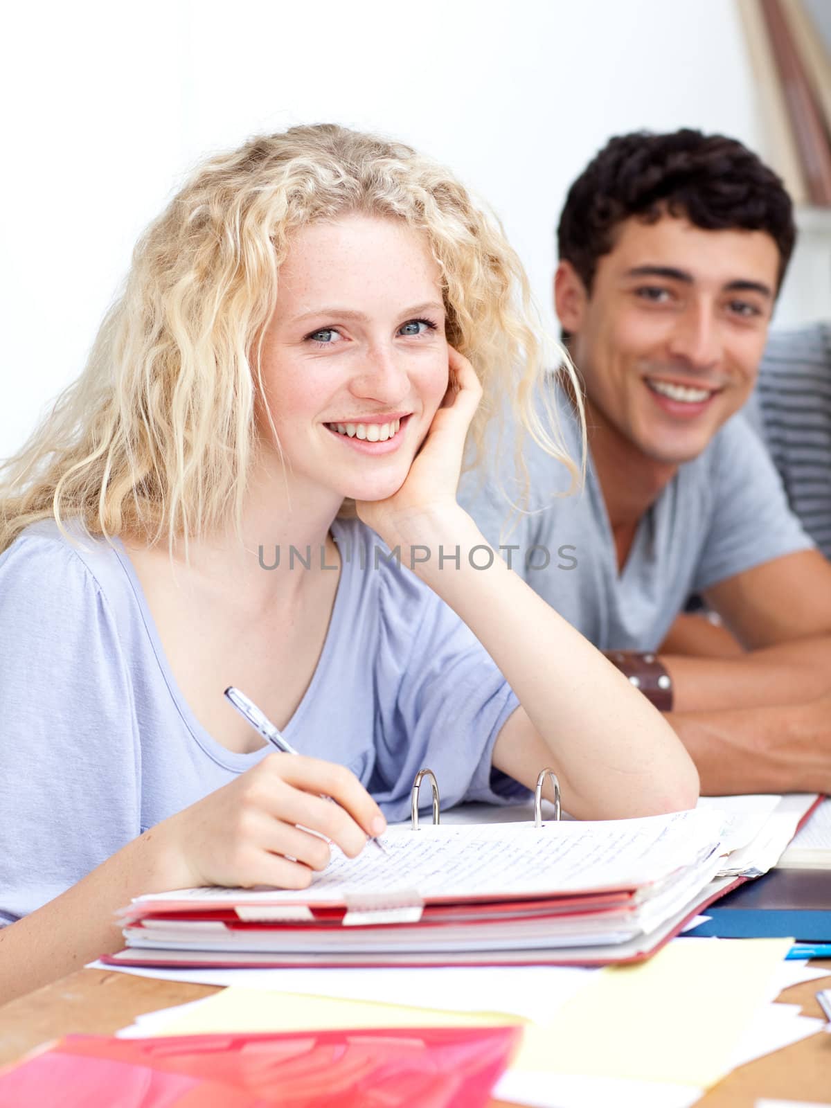 Happy teen girl studying in the library with her friends by Wavebreakmedia
