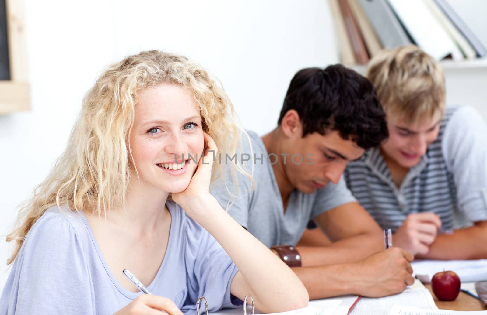 Smiling teen girl studying in the library with her friends by Wavebreakmedia