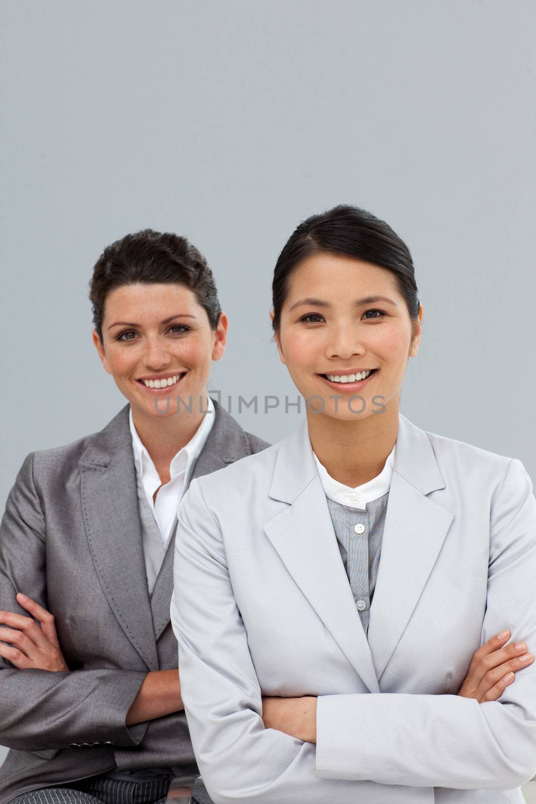 Confident businesswomen with folded arms standing by Wavebreakmedia