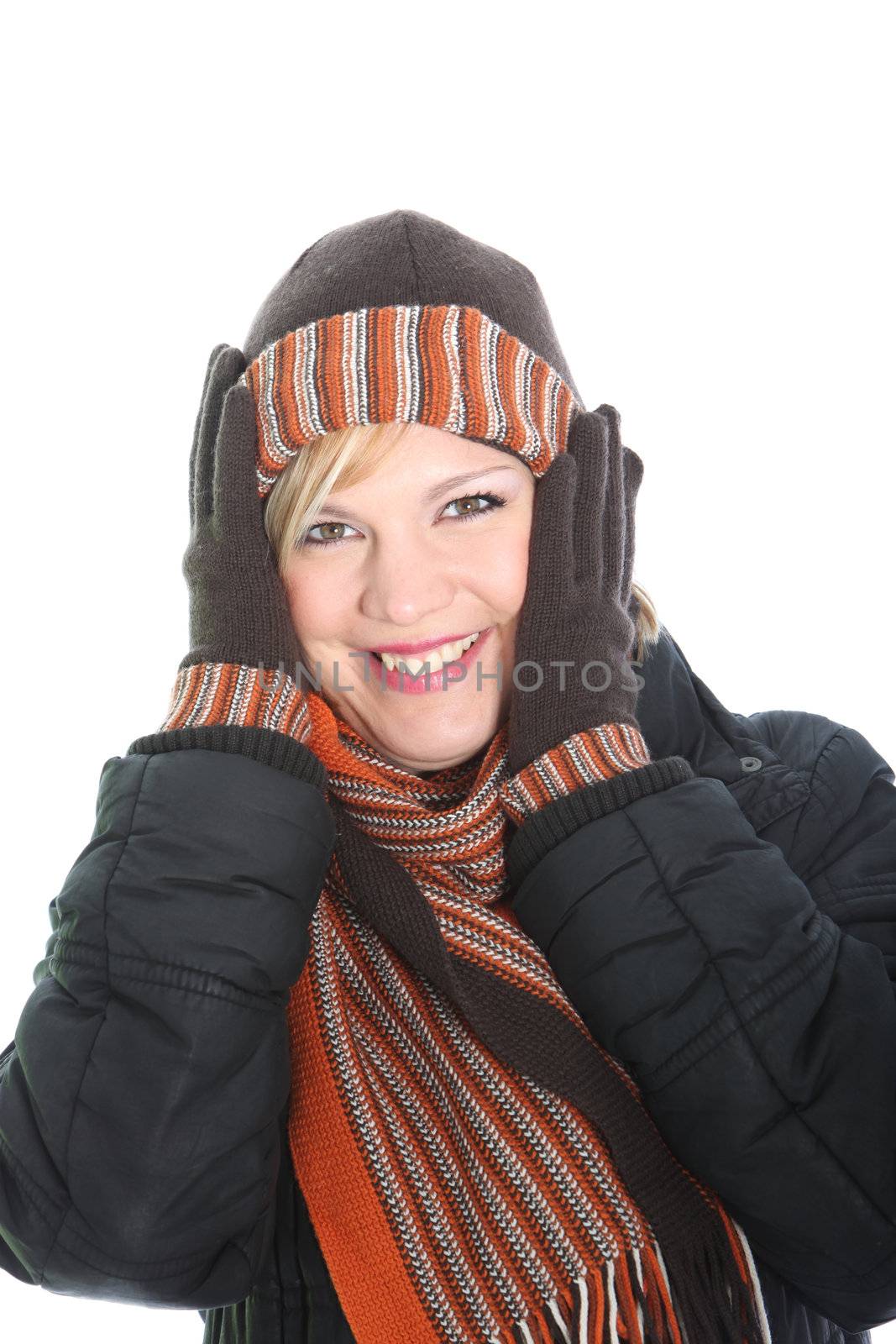 Vivacious woman in winter fashion with matching, hat, gloves and scarf holding her gloved hands to her ears to keep warm
