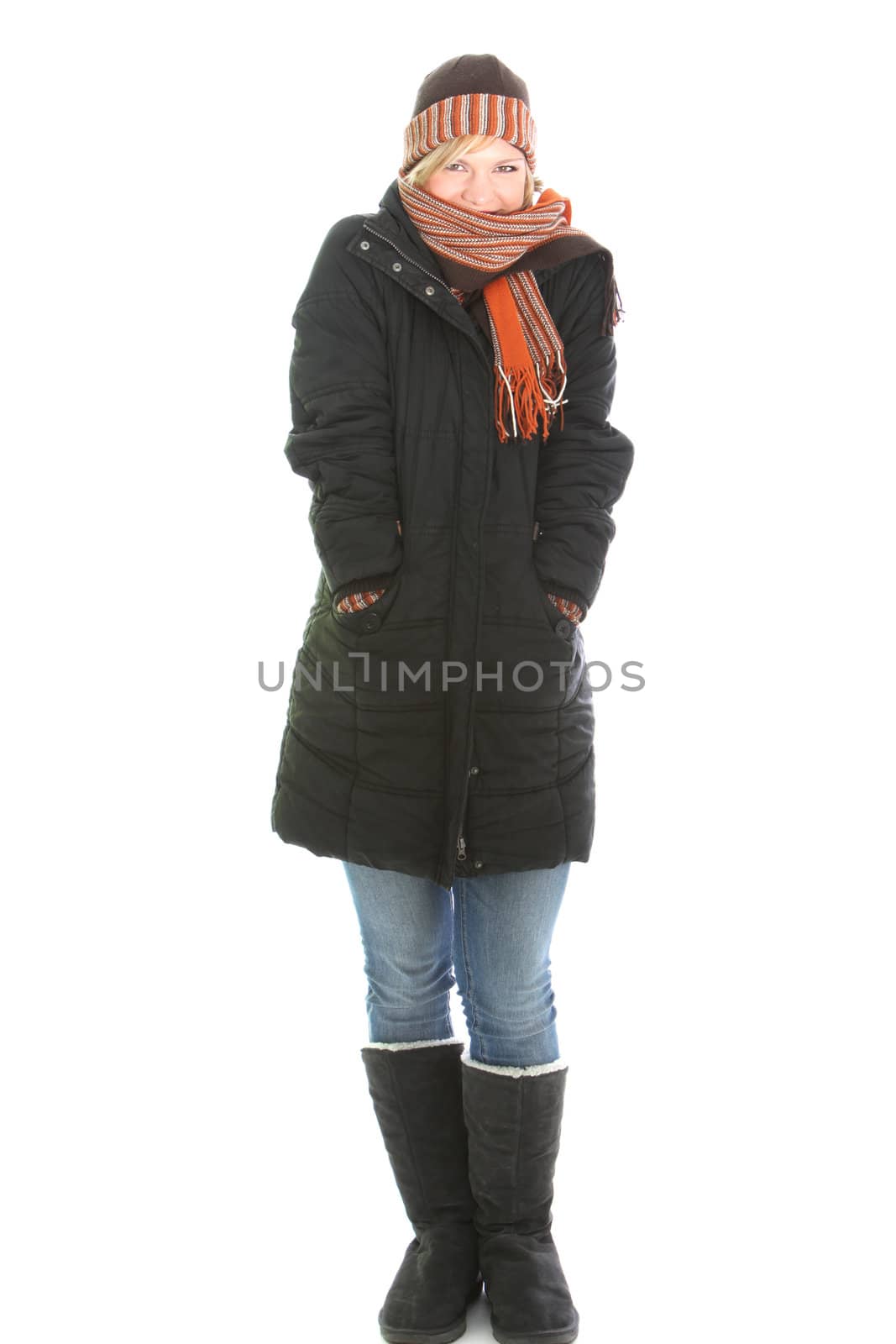 Young woman standing snuggling into the warmth of her warm winter clothing in boots, overcoat, hat and scarf