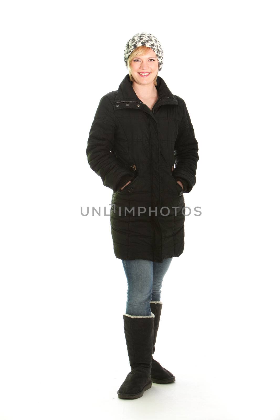 Full length studio portrait of a smiling woman in warm winter outfit with fur lined boots, a thick overcoat and knitted cap isolated on white