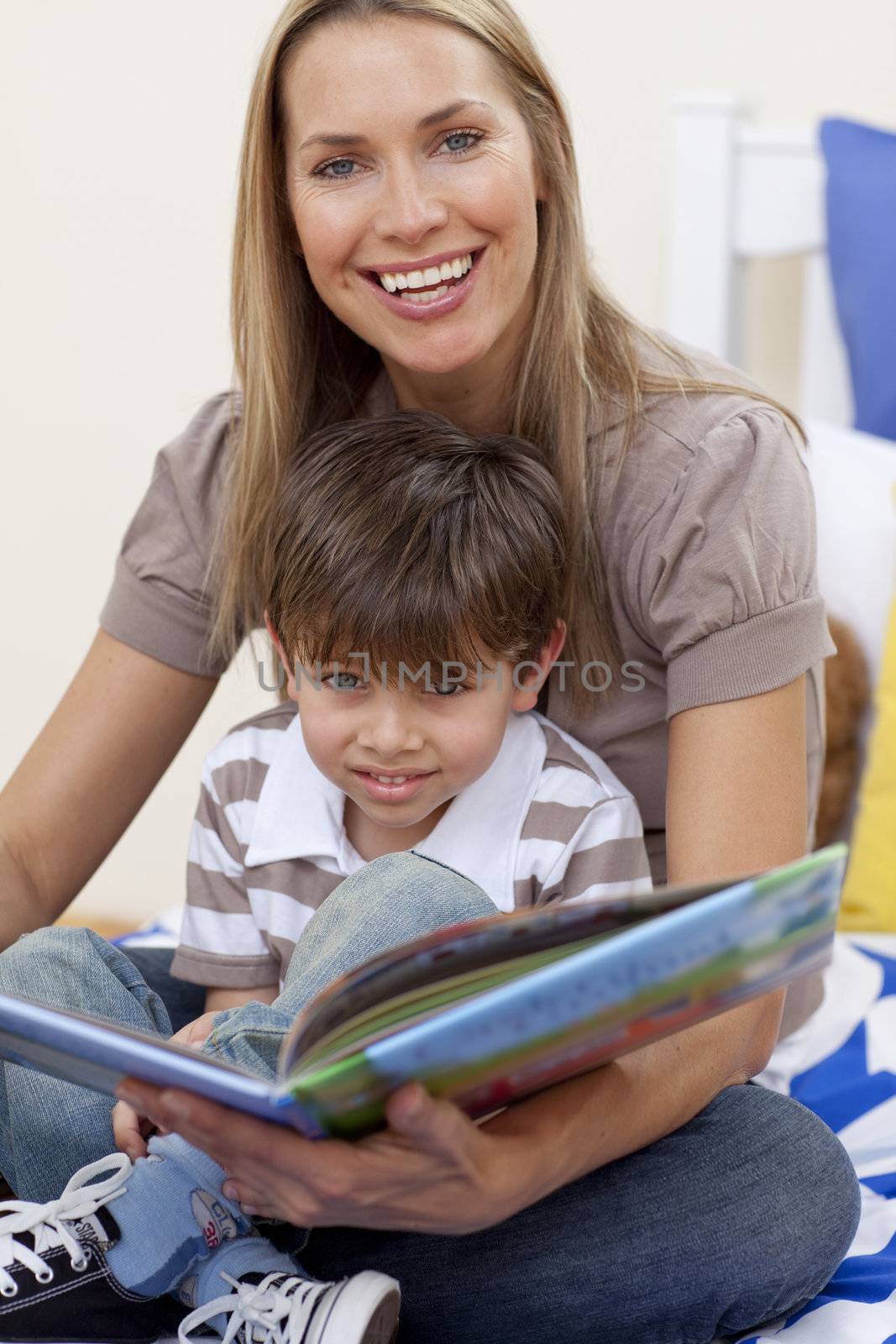 Smiling motherr reading a book with her son in bedroom