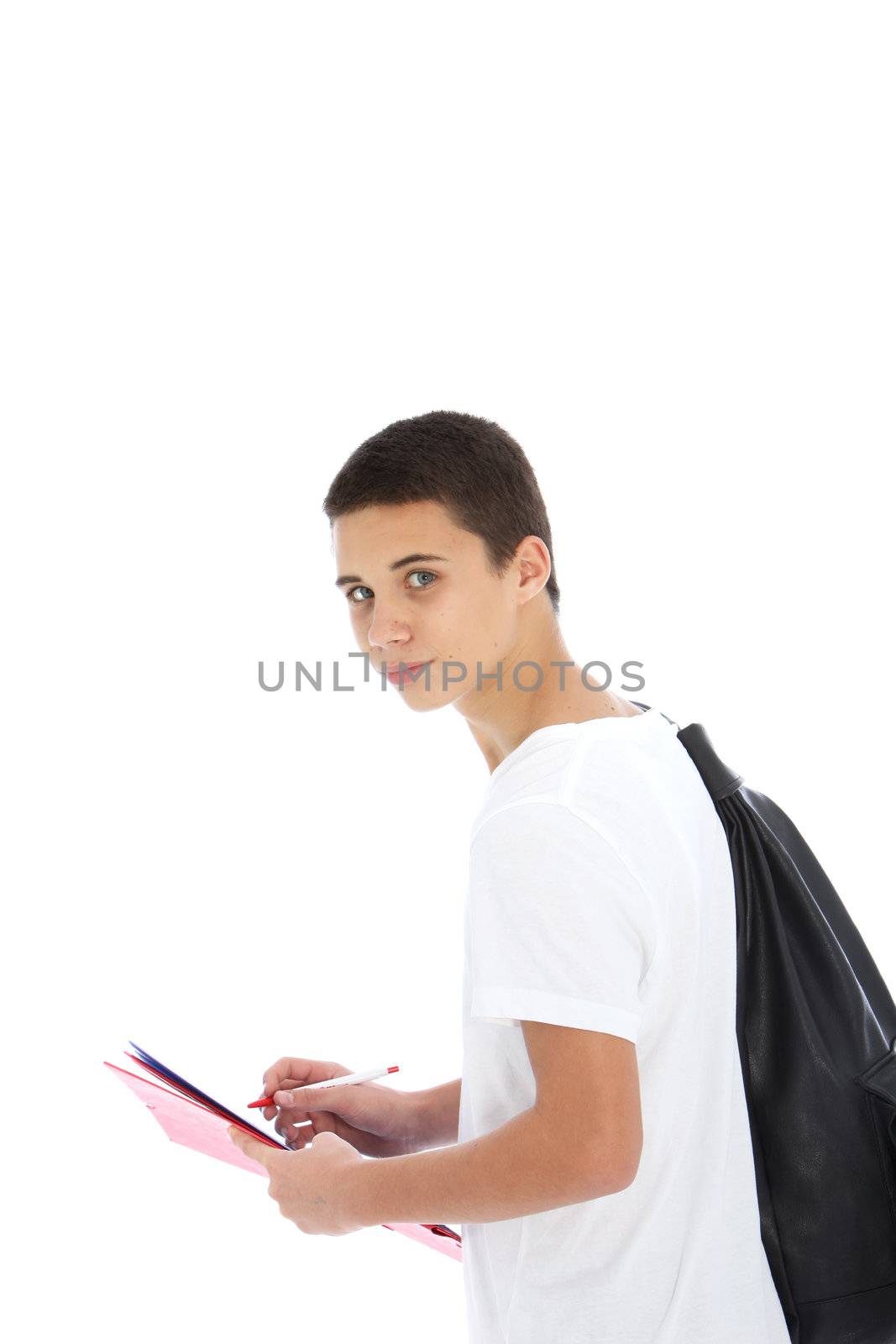 Teenage student boy with a large kit bag slung over his shoulder writing notes on a handheld folder, standing sideways looking at the camera isolated on white