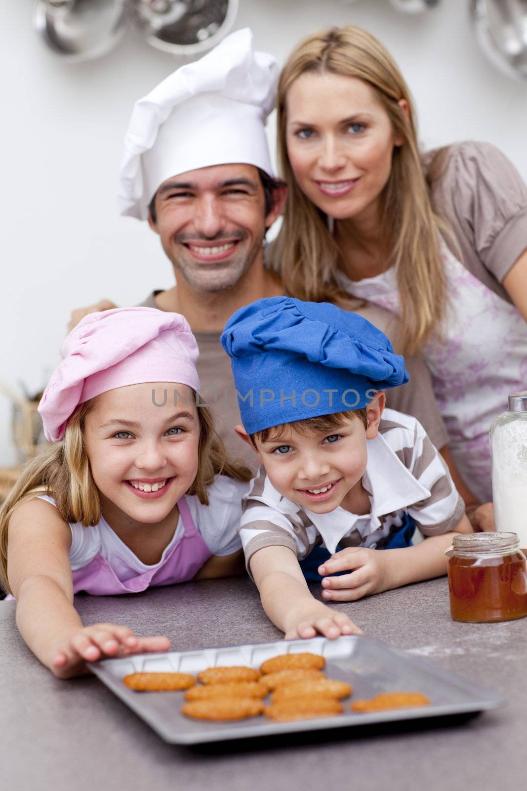Happy children and parents eating cookies after baking in the kitchen