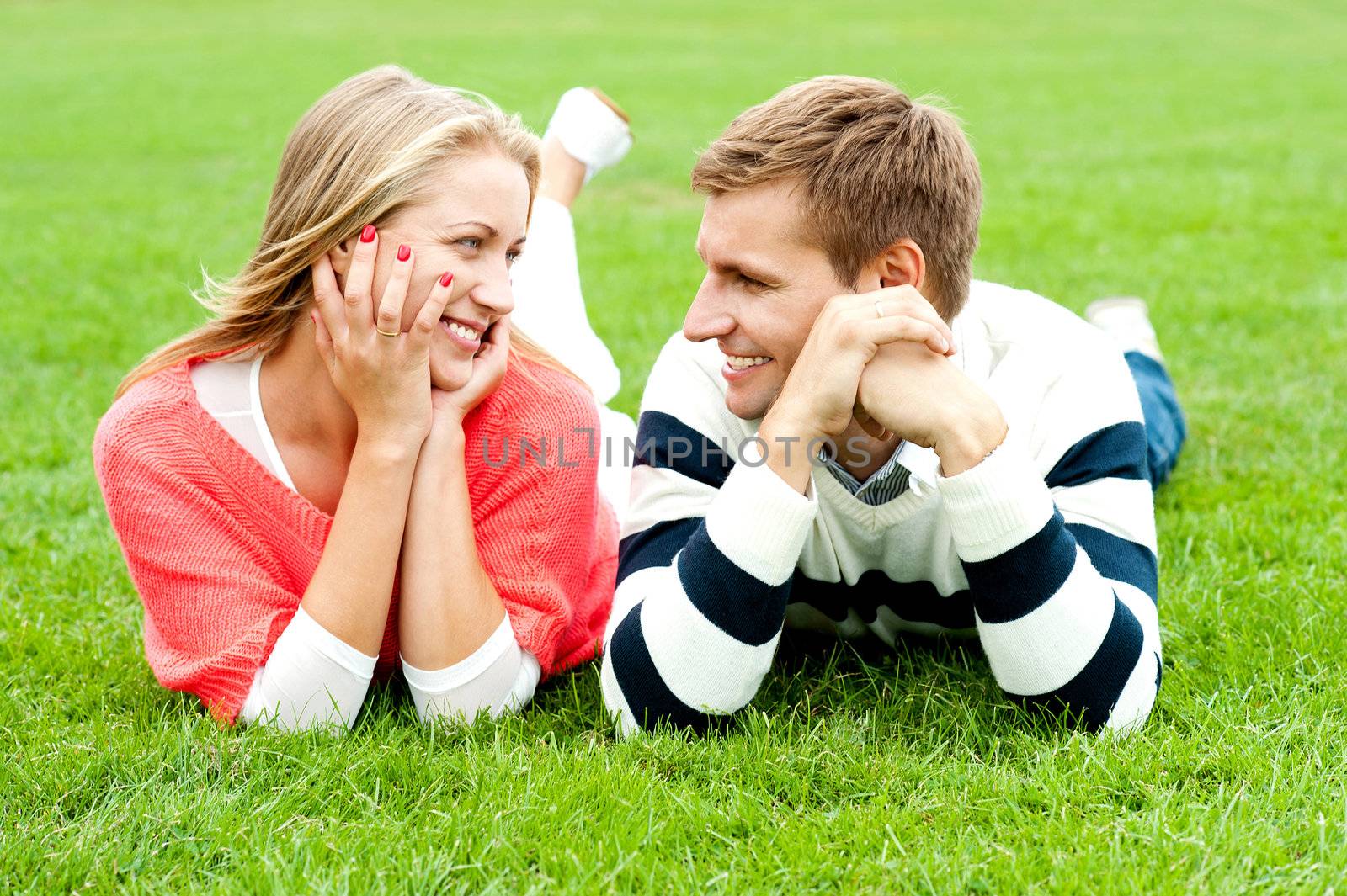 Happy smiling couple relaxing on green grass. Outdoor shot