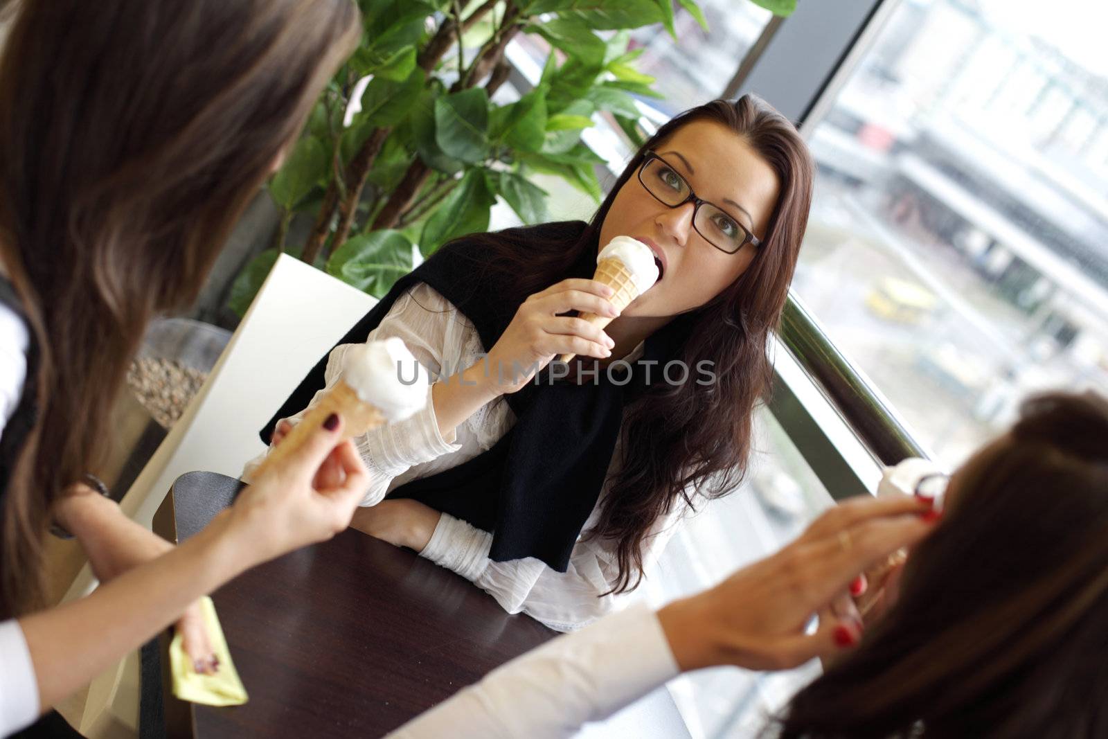 happy smiling women on foreground licking ice cream 