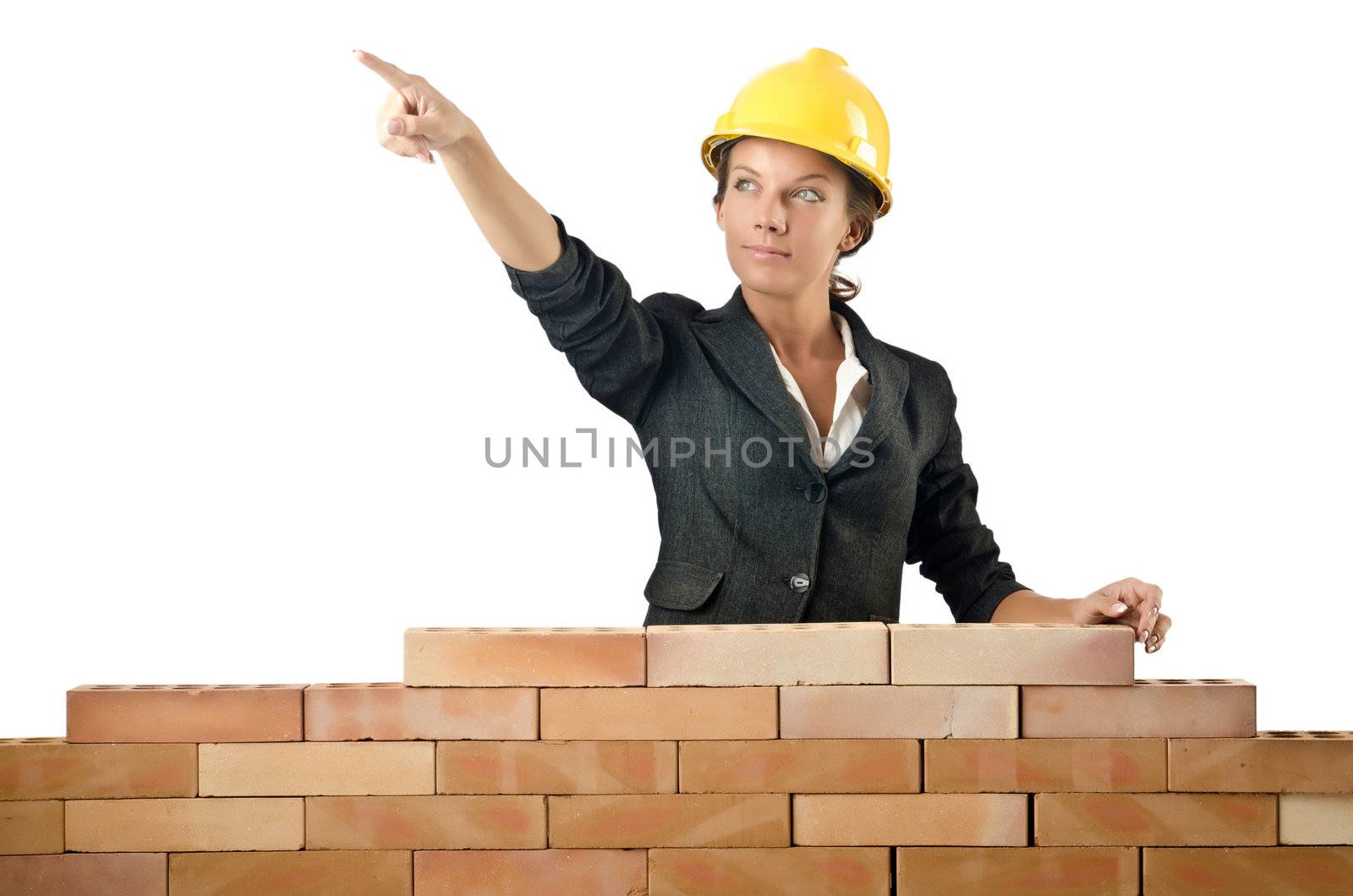 Young female builder near brick wall