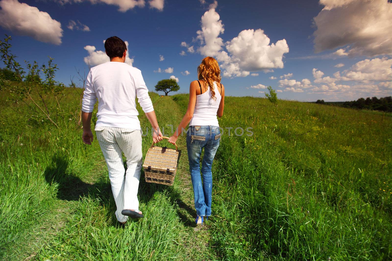 man and woman walk on picnic in green grass
