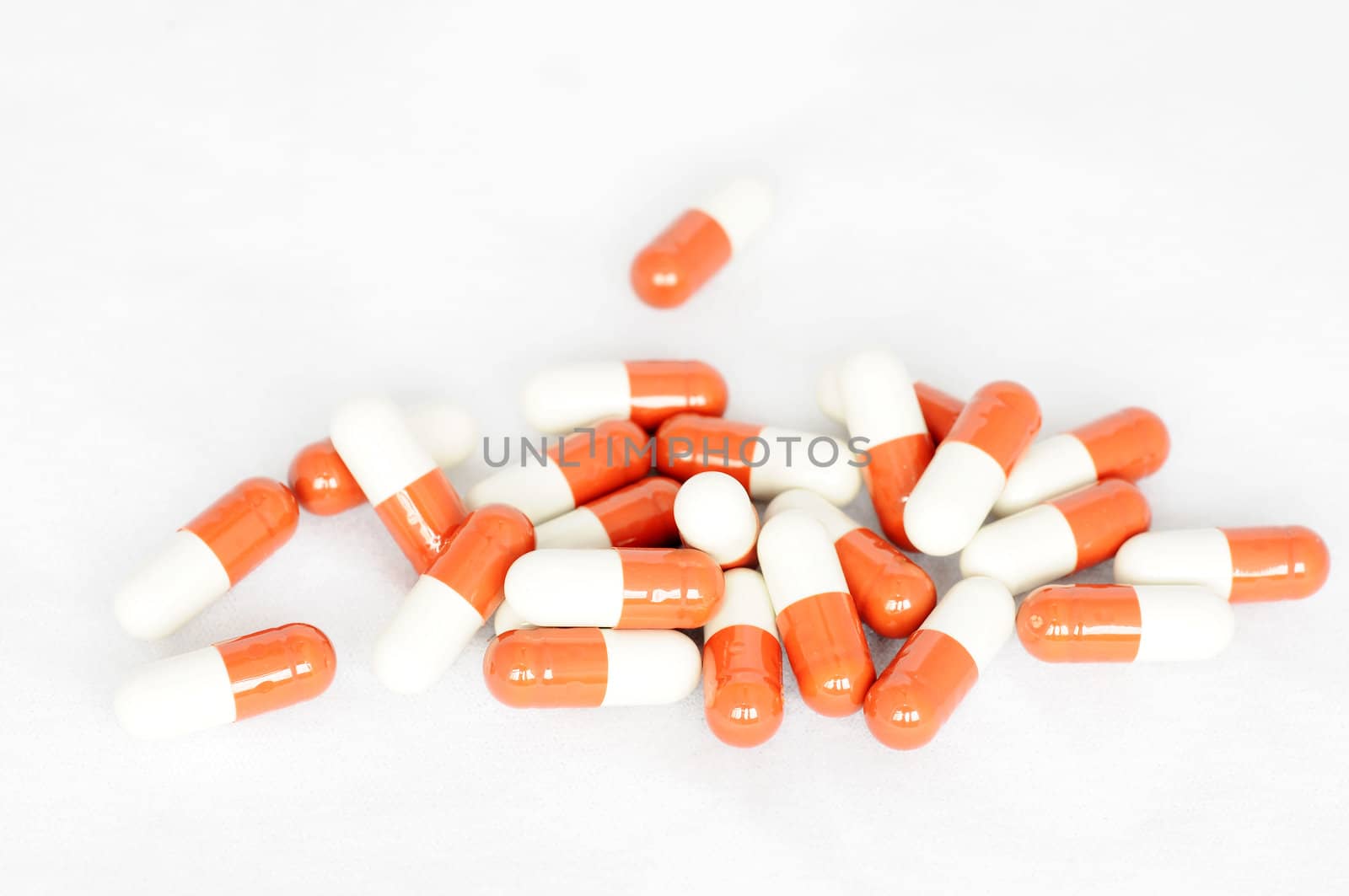 Group of red-and-white capsules on a white background