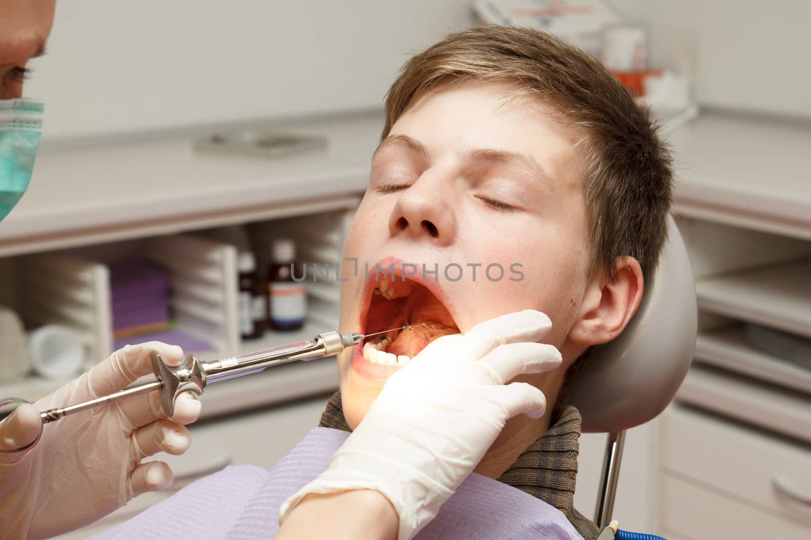 Boy at the dentist with a large syringe receiving anesthesia