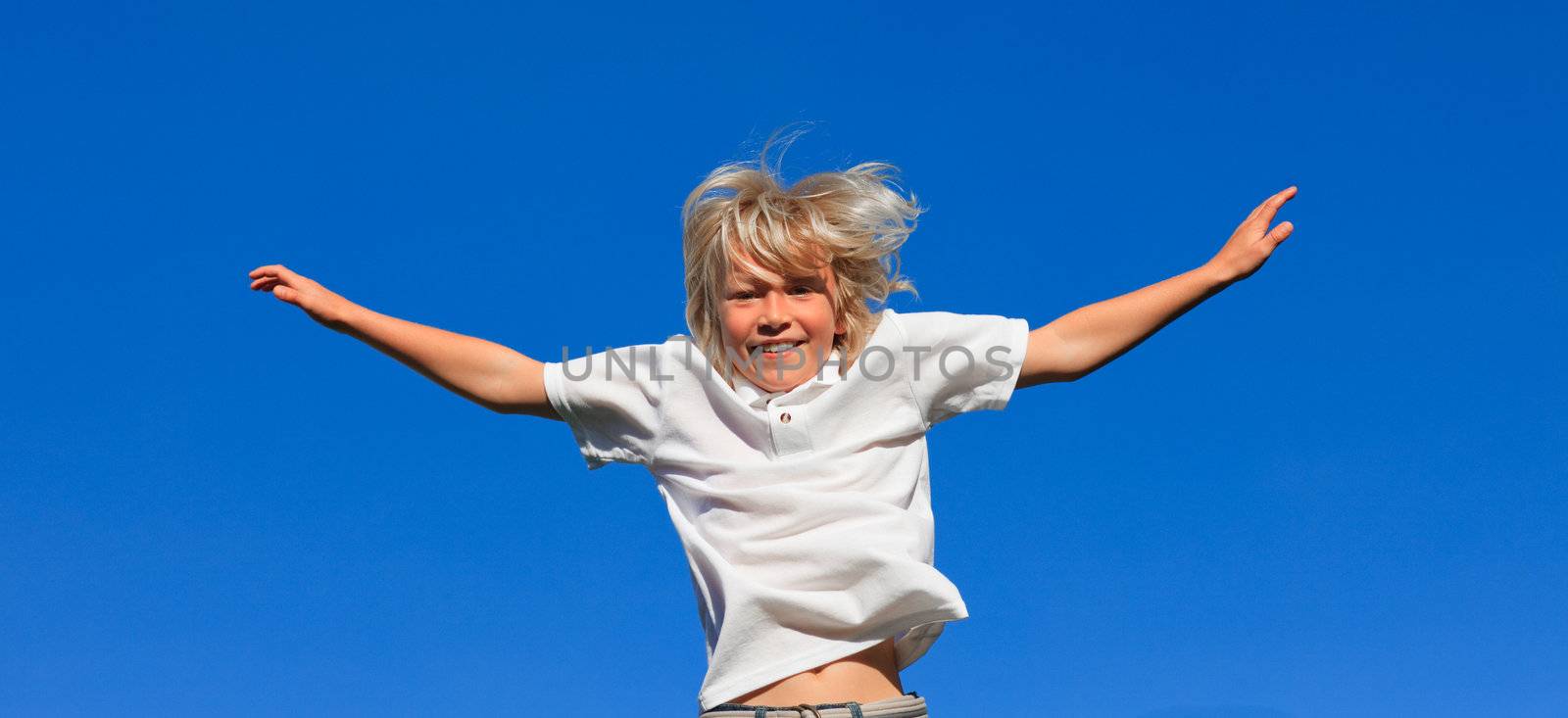 Cute Kid Jumping in the air outdoor on a blue sky background