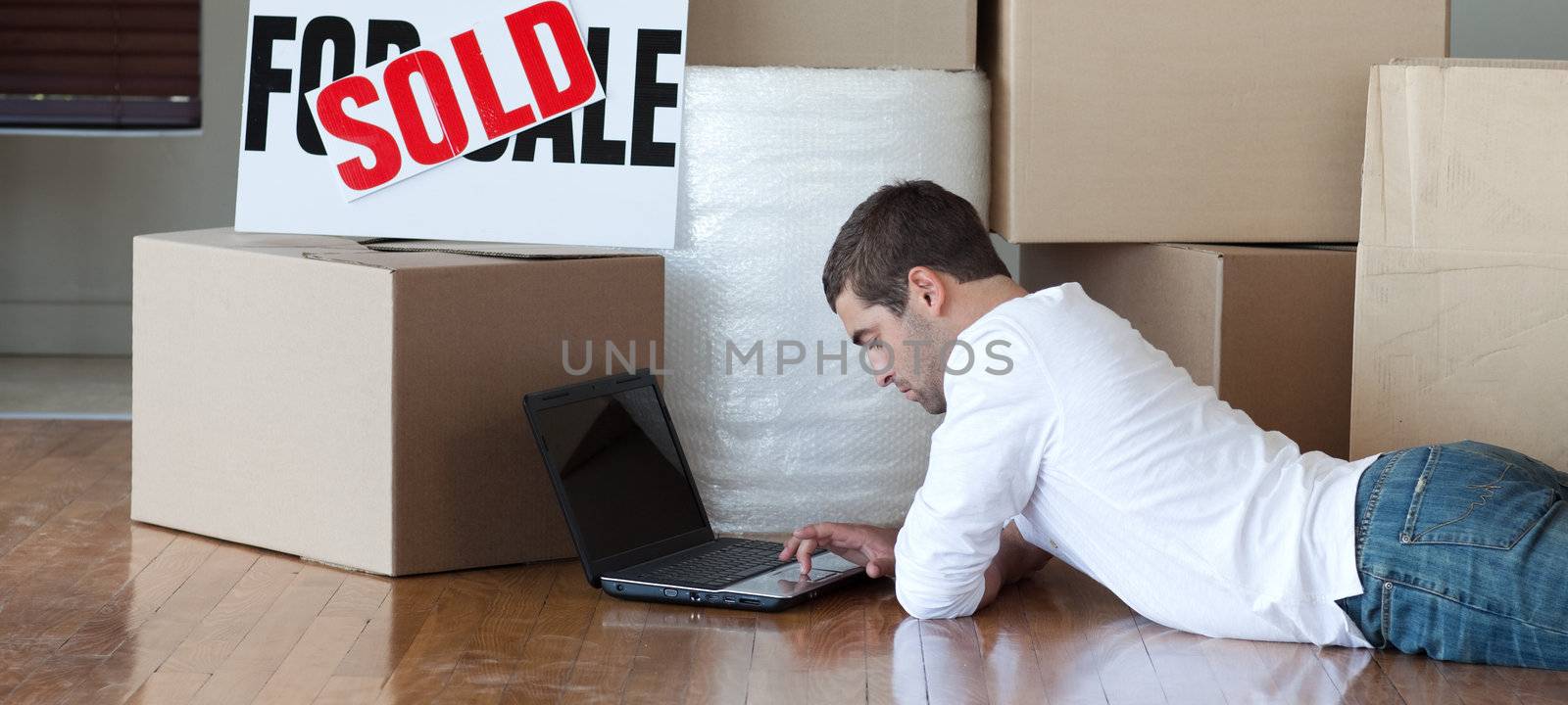 Concentrated man working at his laptop  in his new house