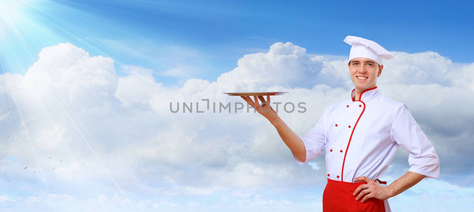 Portrait of a young male cook in red apron against colour background