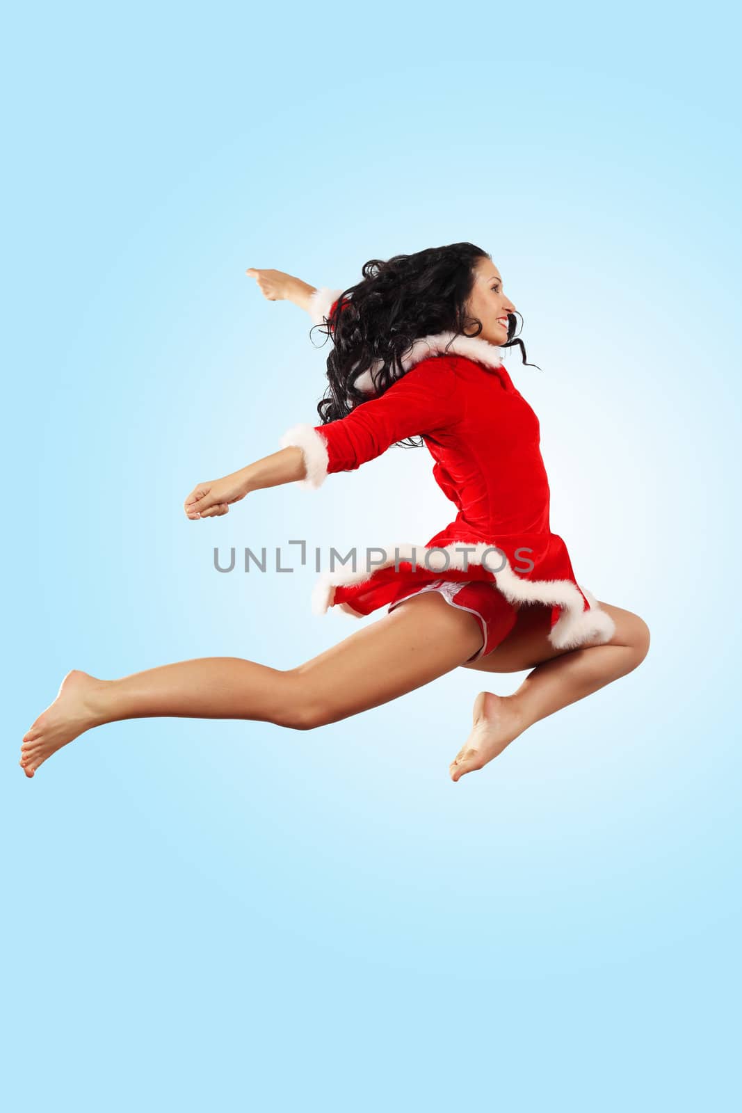 Happy smiling woman in red xmas costume jumping high