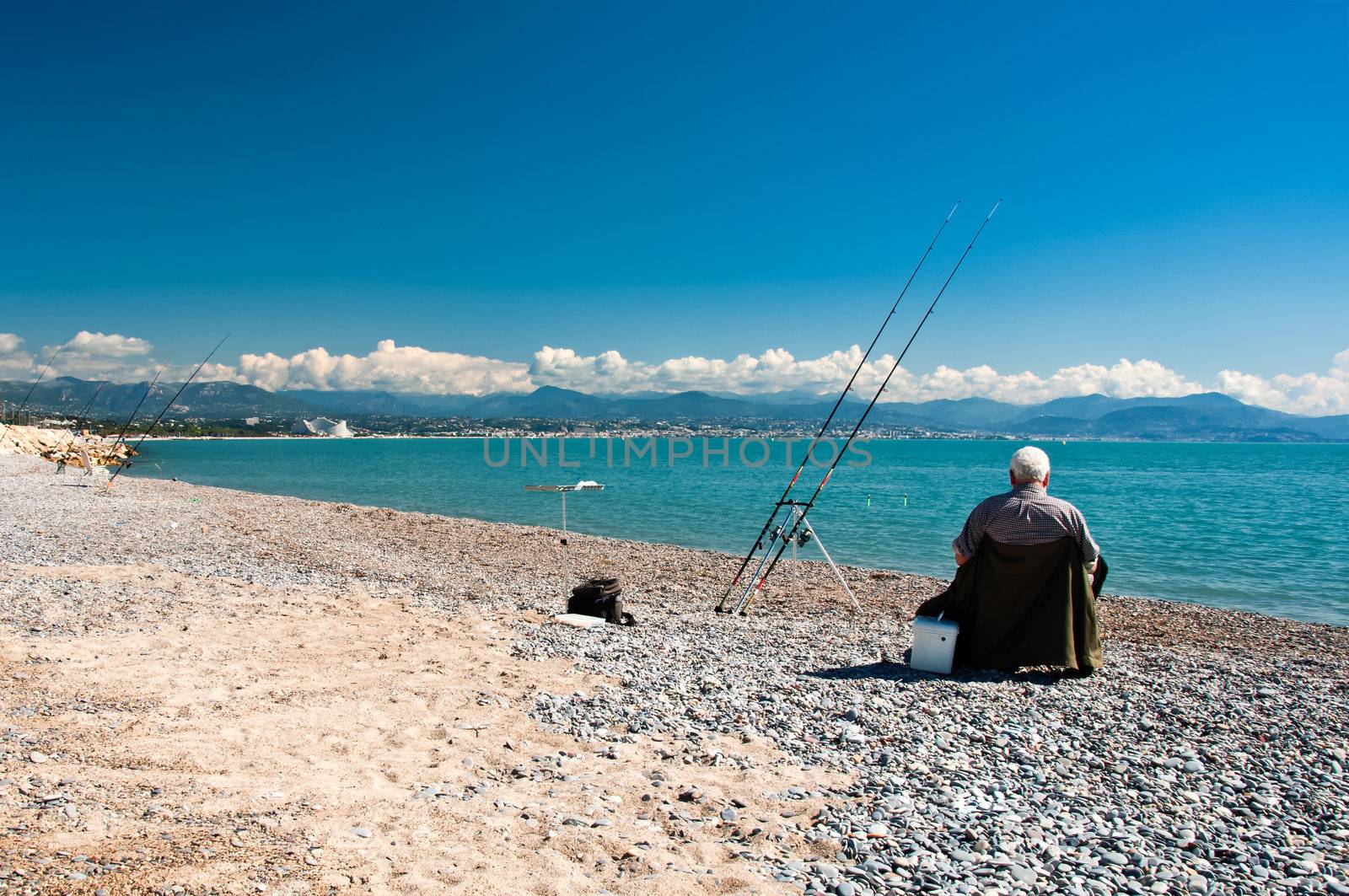 Senior fisherman at blue sea coast during sunny day, blue sky and white clouds