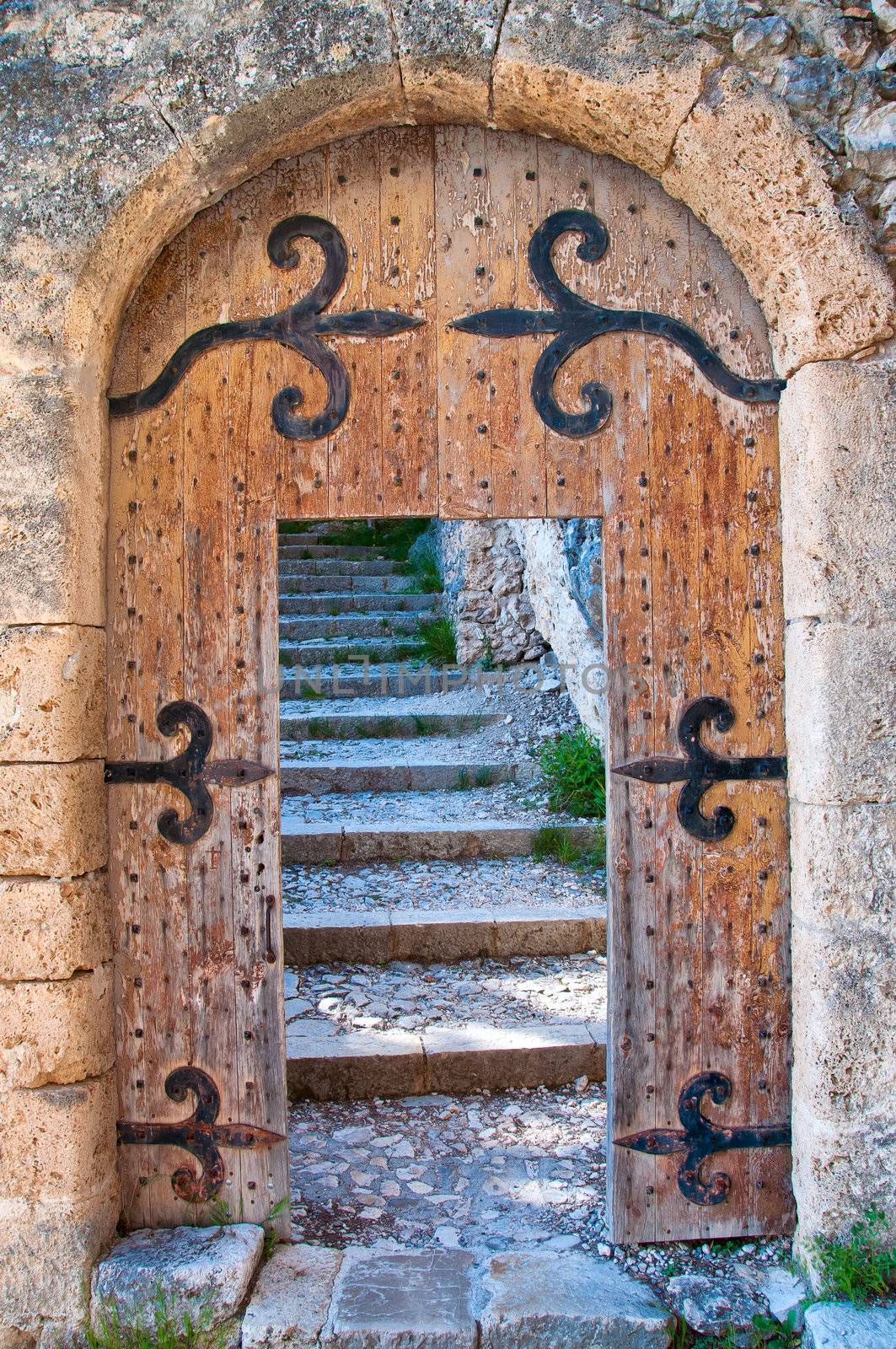 Old open wooden door with stone stairs in the background