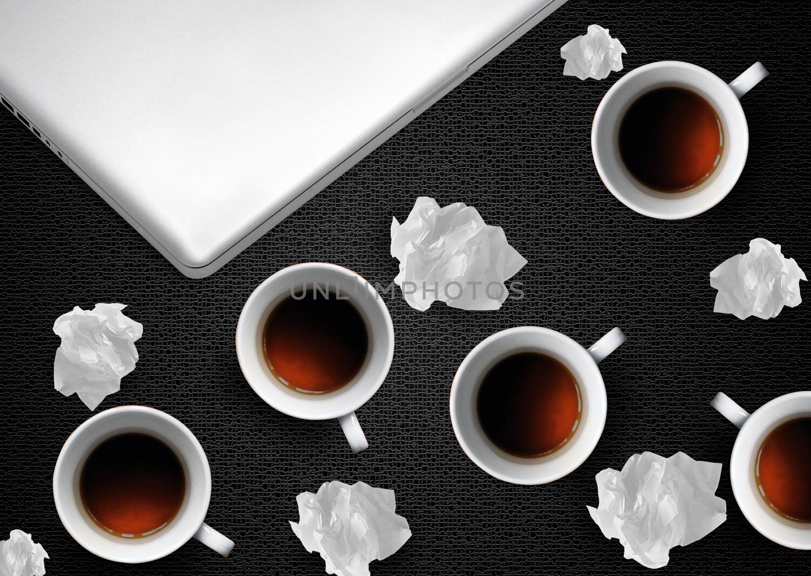 Crumpled colorful papers with laptop and coffee on black desktop.