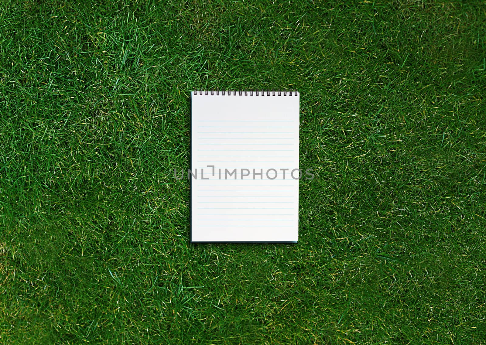 blank opened notebook on grassland .