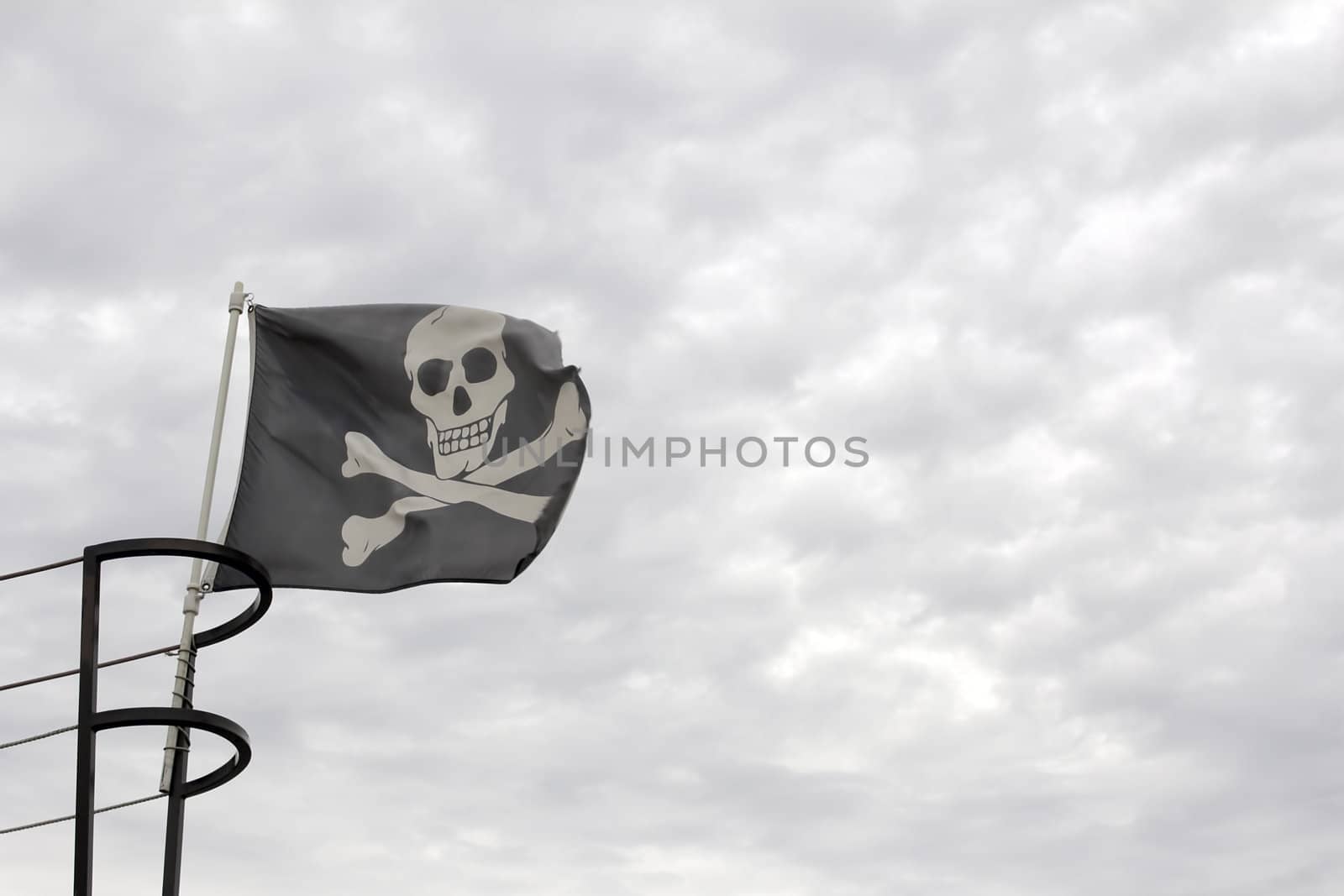 Pirate Ship Jolly Roger Skull with Crossbones Flag against Cloudy Sky Background