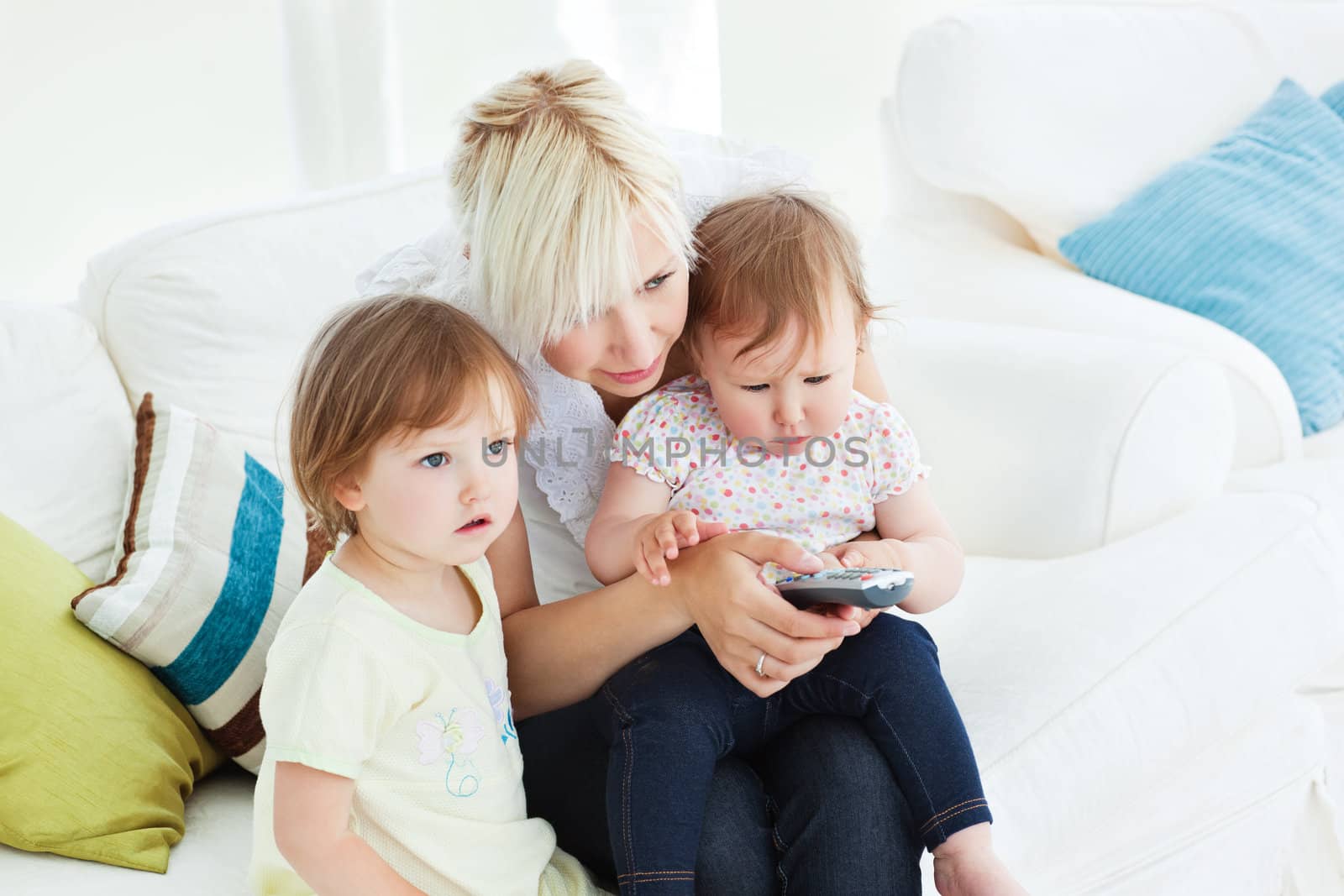 happy woman using a remote with her girl in the living-room at home