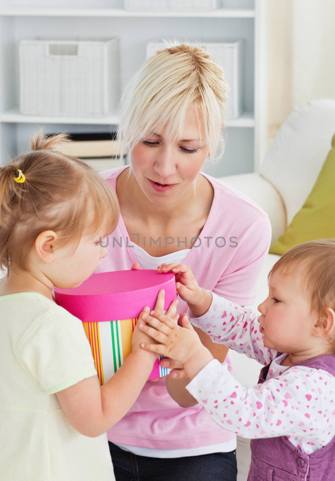 Smiling woman offering a gift to her girl in the living-room at home