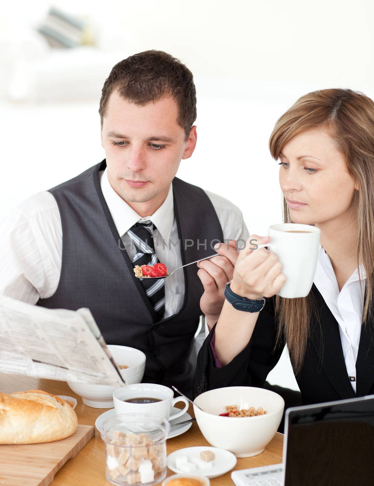 Young couple of business people reading a newspaper while having by Wavebreakmedia