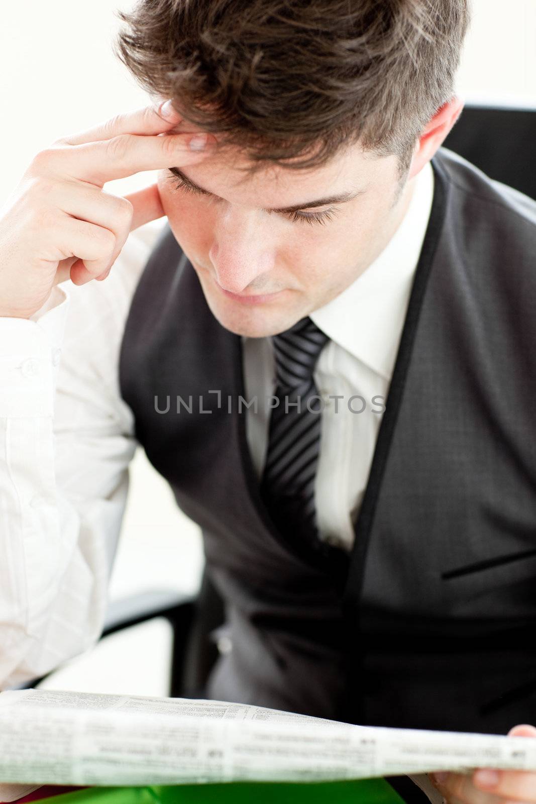 Concentrated businessman reading a newspaper sitting in his office