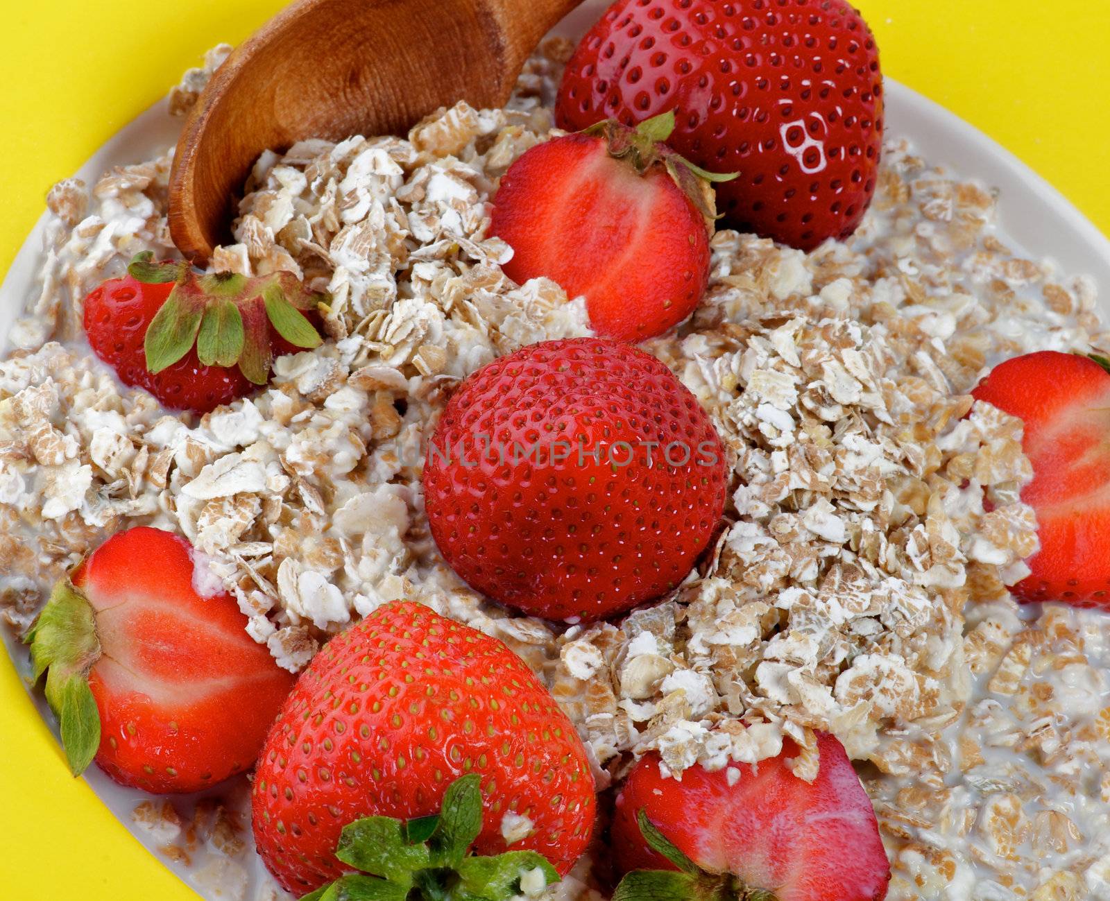 Strawberries with Flakes and Milk in Yellow Plate with Wooden Spoon closeup