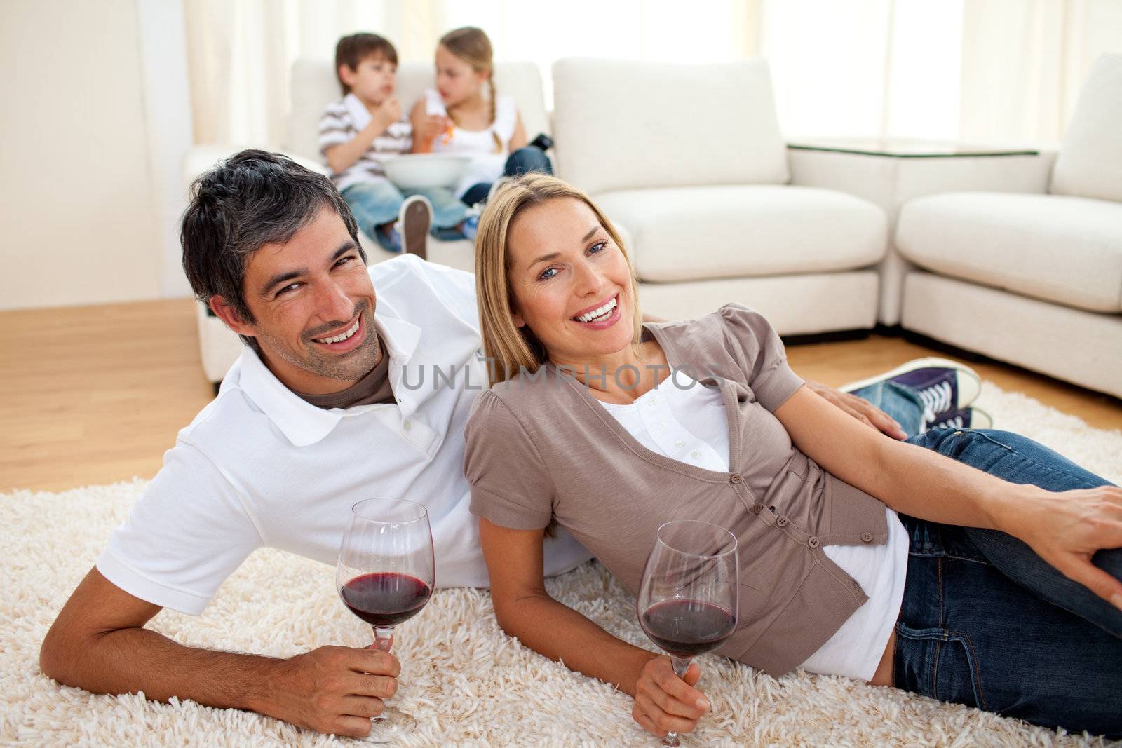 Affectionate lovers drinking wine lying on the floor by Wavebreakmedia