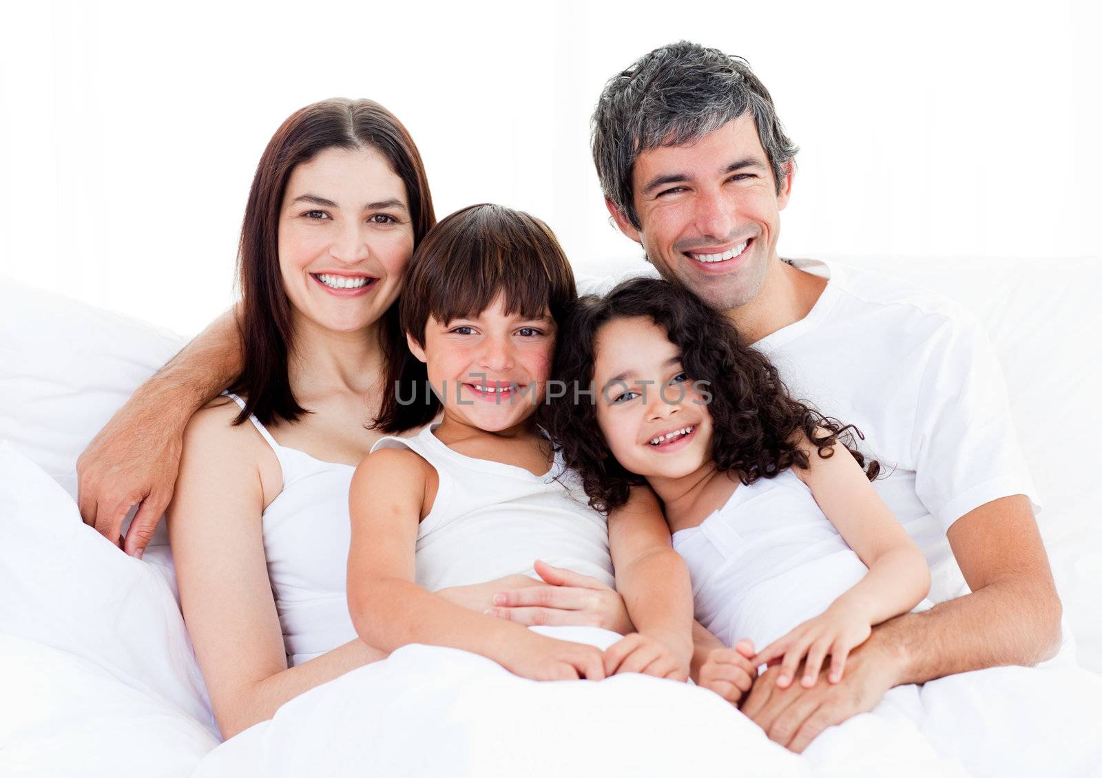 Portrait of a happy family sitting on a bed at home