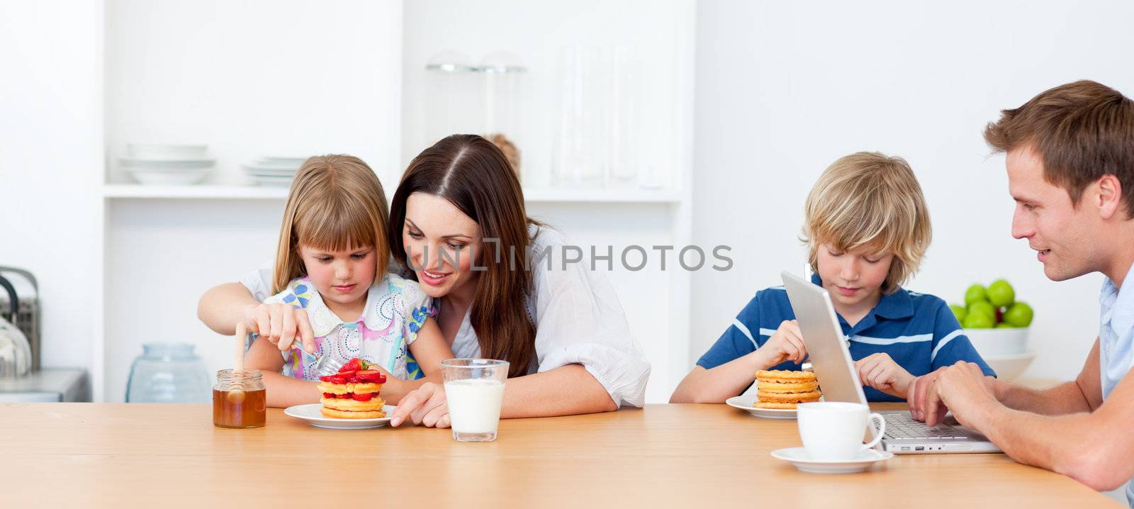 Happy family eating breakfast in the kitchen by Wavebreakmedia