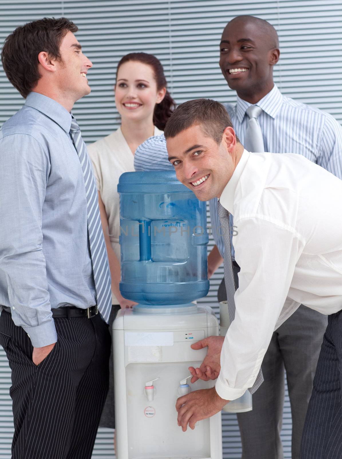 Busines colleagues talking around water cooler in workplace