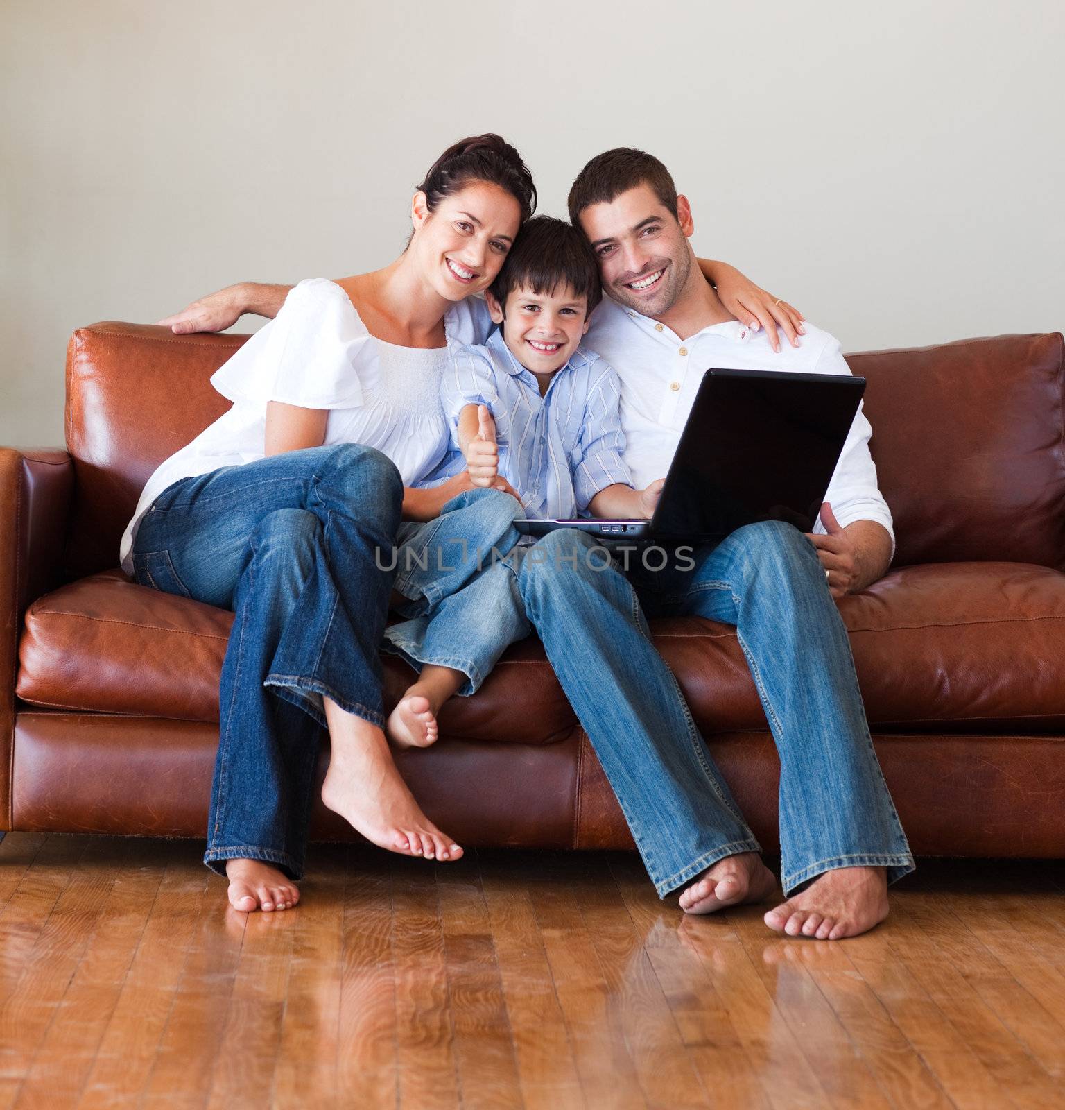 Parents and kid using a laptop with thumbs up on a couch
