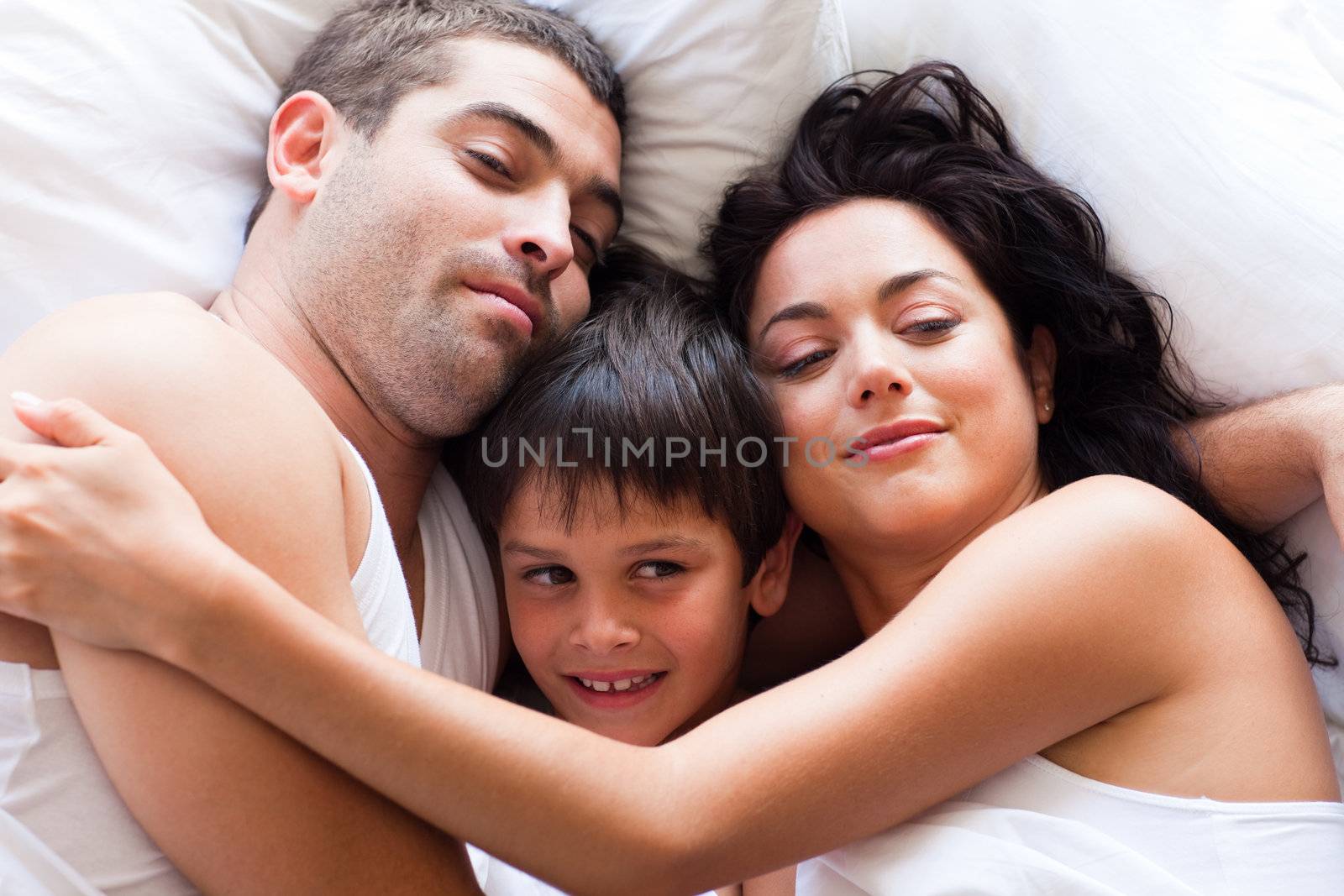 Portrait of a happy family sleeping in bed  by Wavebreakmedia