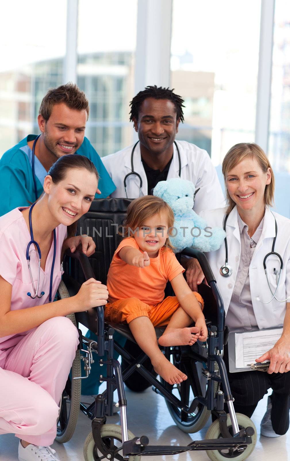 Baby girl in a wheelchair with medical team by Wavebreakmedia