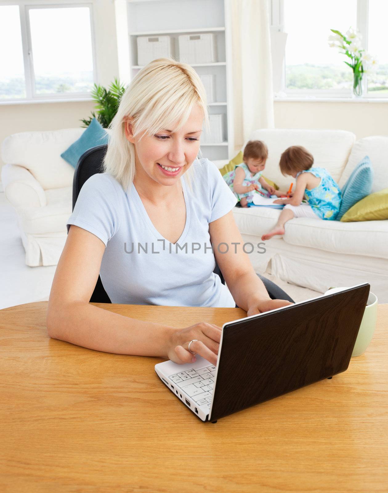Busy woman working with her children at laptop in living room