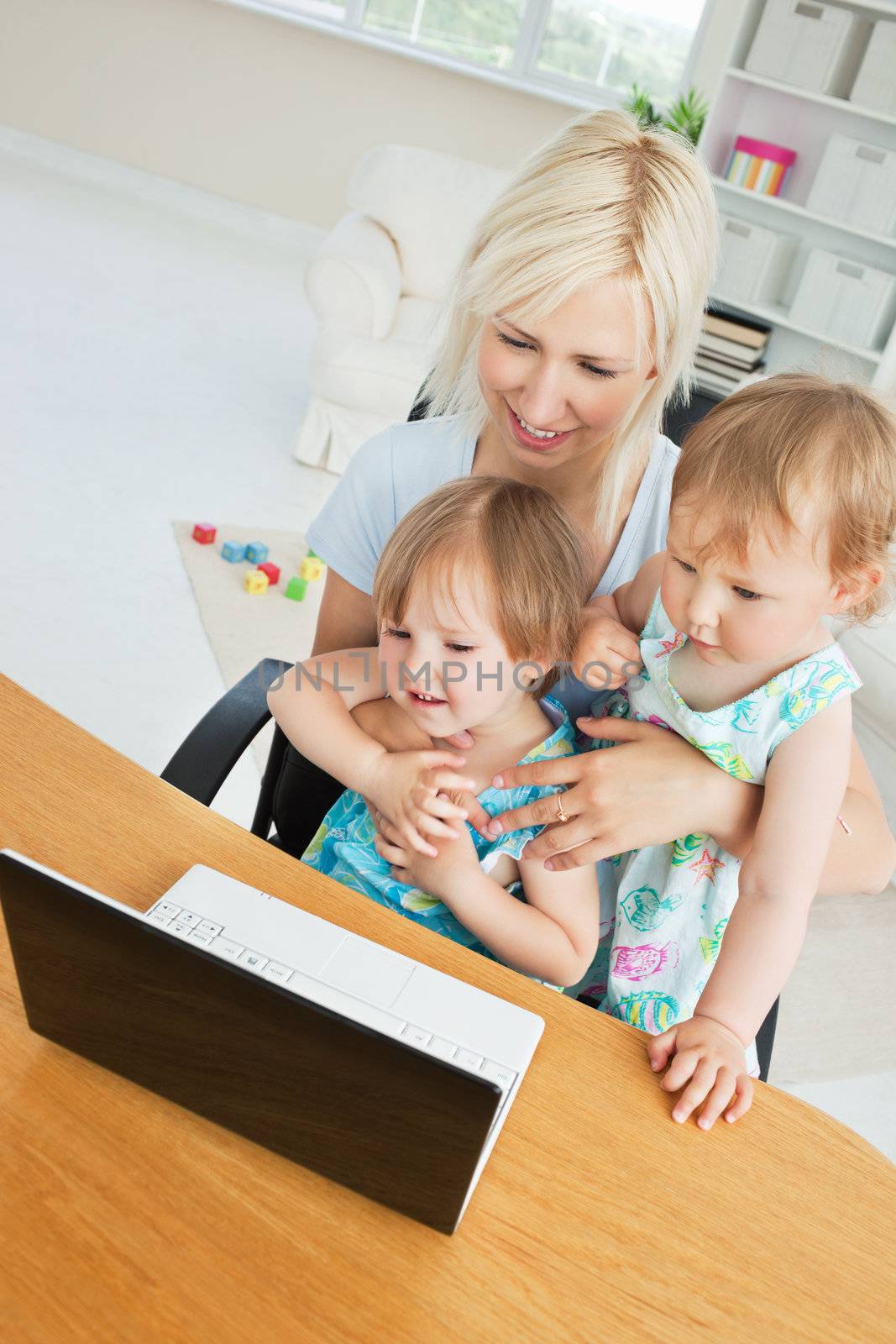 Radiant woman working with her children at laptop in living room