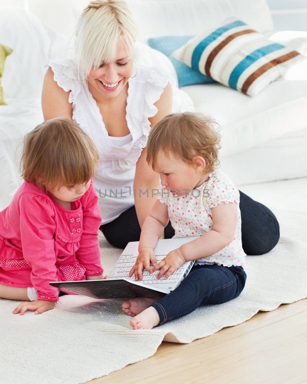 Pretty woman working with her children at laptop in living room
