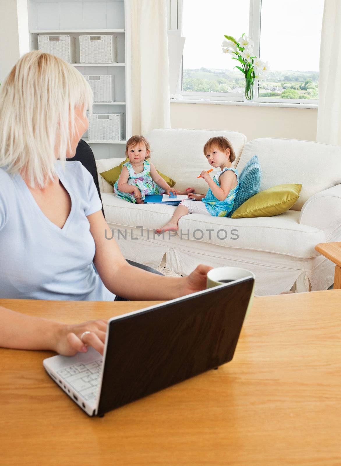 Blond mother working at laptop by Wavebreakmedia