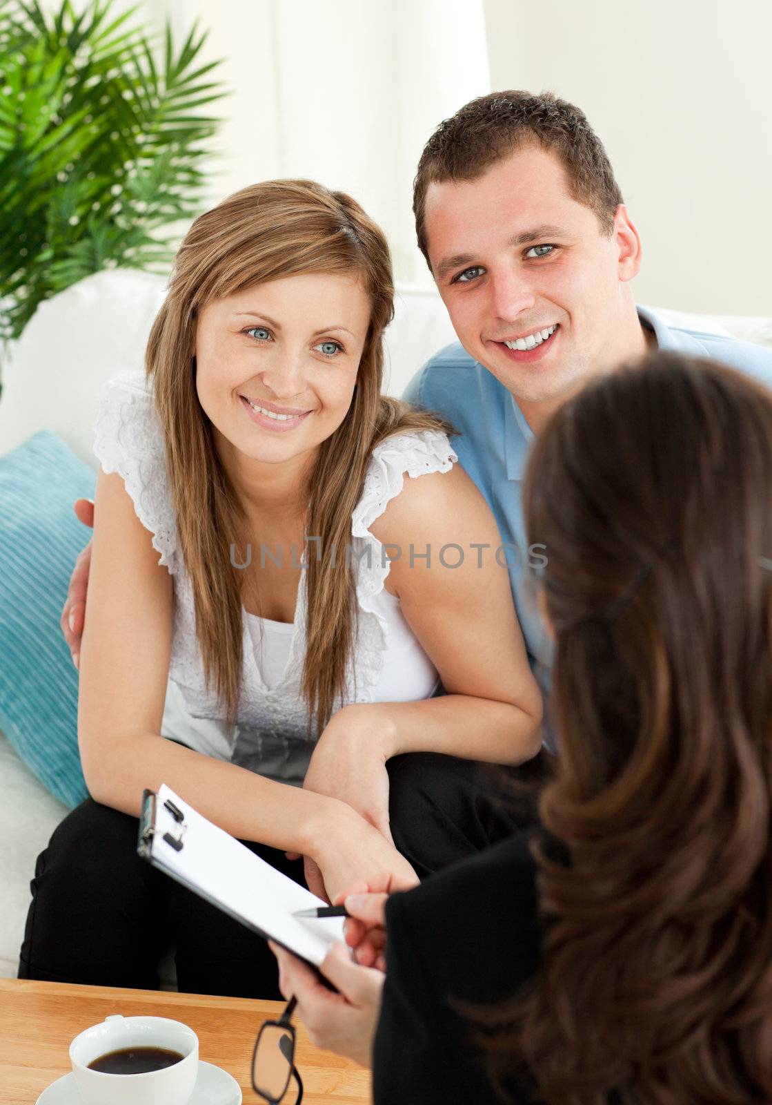 Bright couple concluding a car contract with a female dealer in the living room