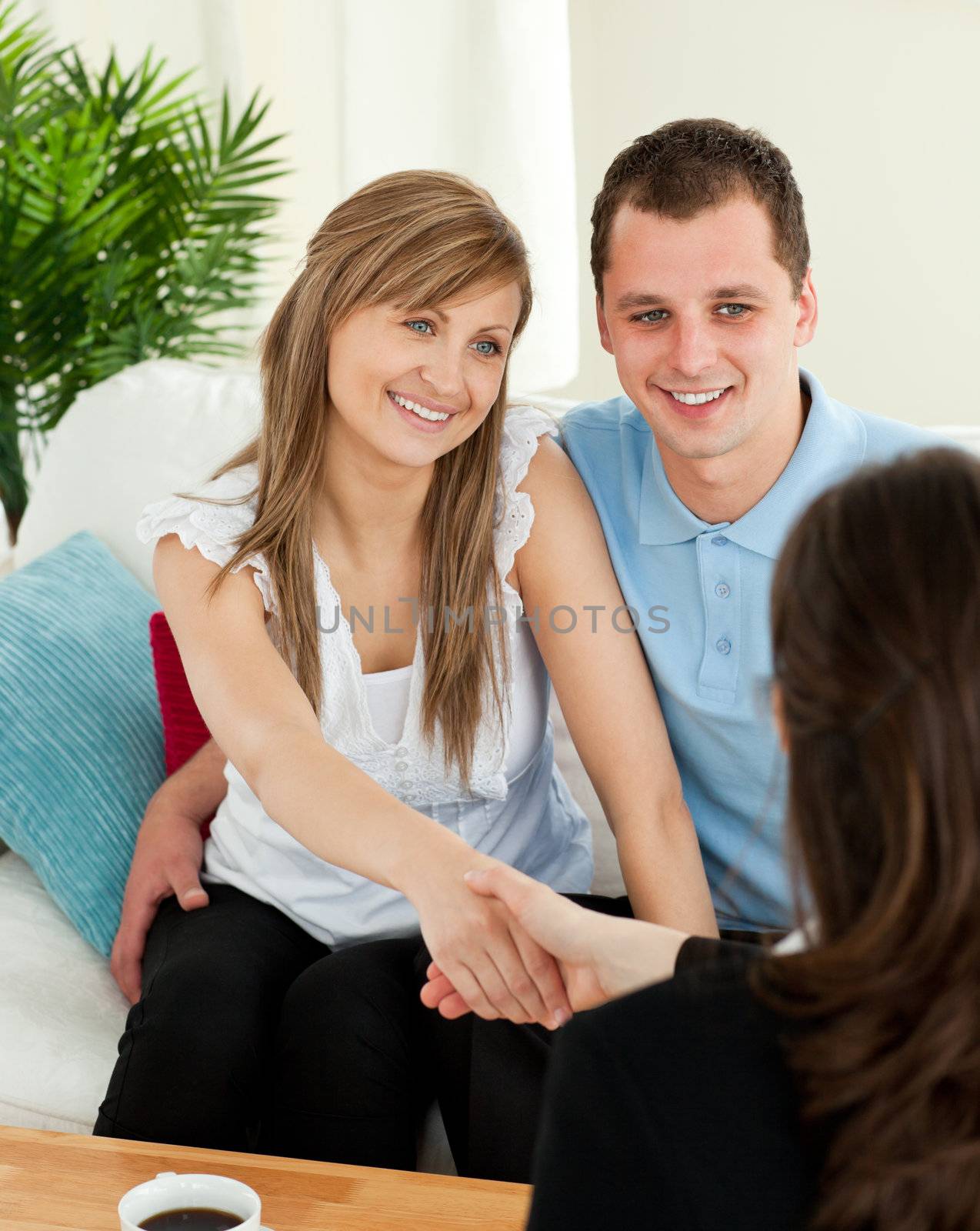 Happy couple concluding a contract with a female dealer by Wavebreakmedia