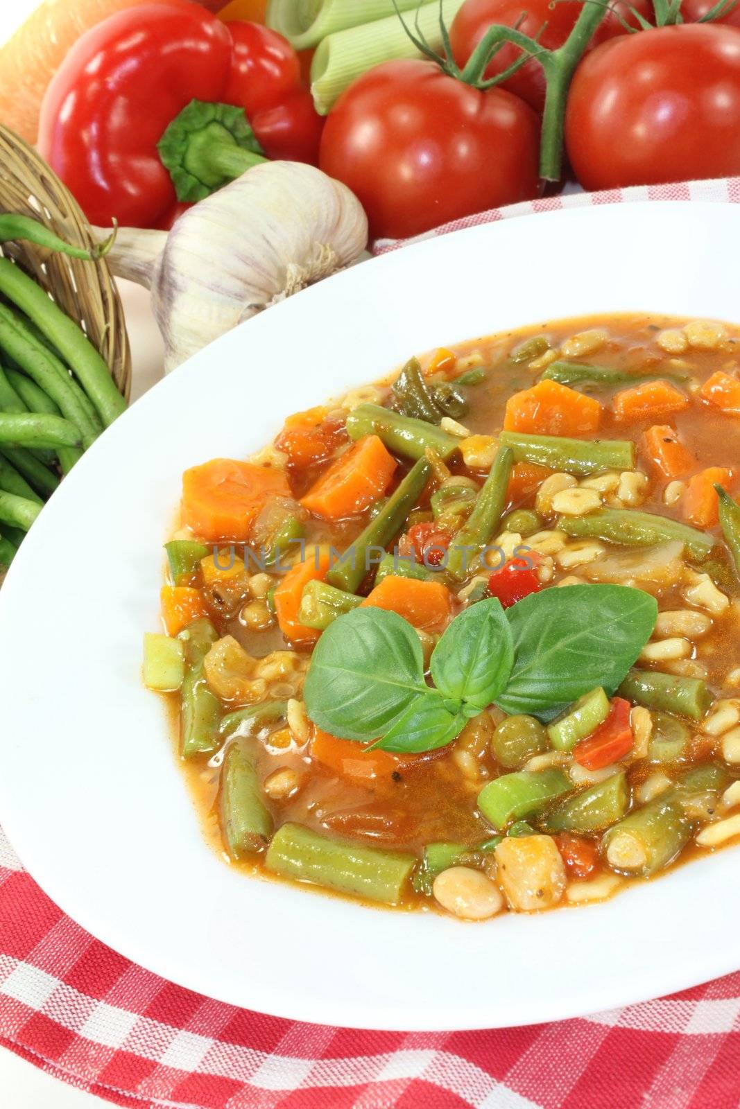 Minestrone with beans, carrots, potatoes, leeks and garlic on a light background